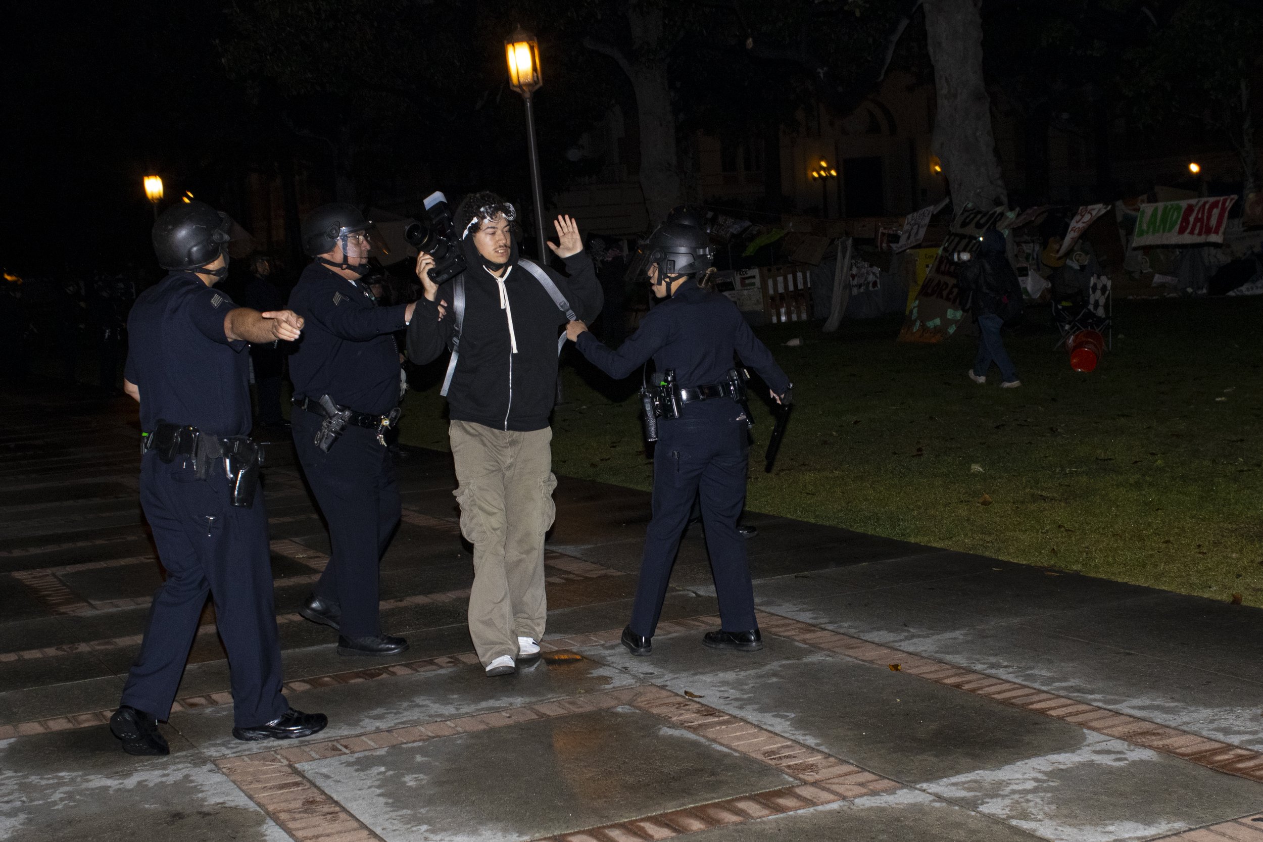  A protester from the University of Southern California Divest from Death coalition is pushed by  University of Southern California Department of Security Officers toward the rest of the protesters after being told to disperse on Sunday, May 5, 2024,