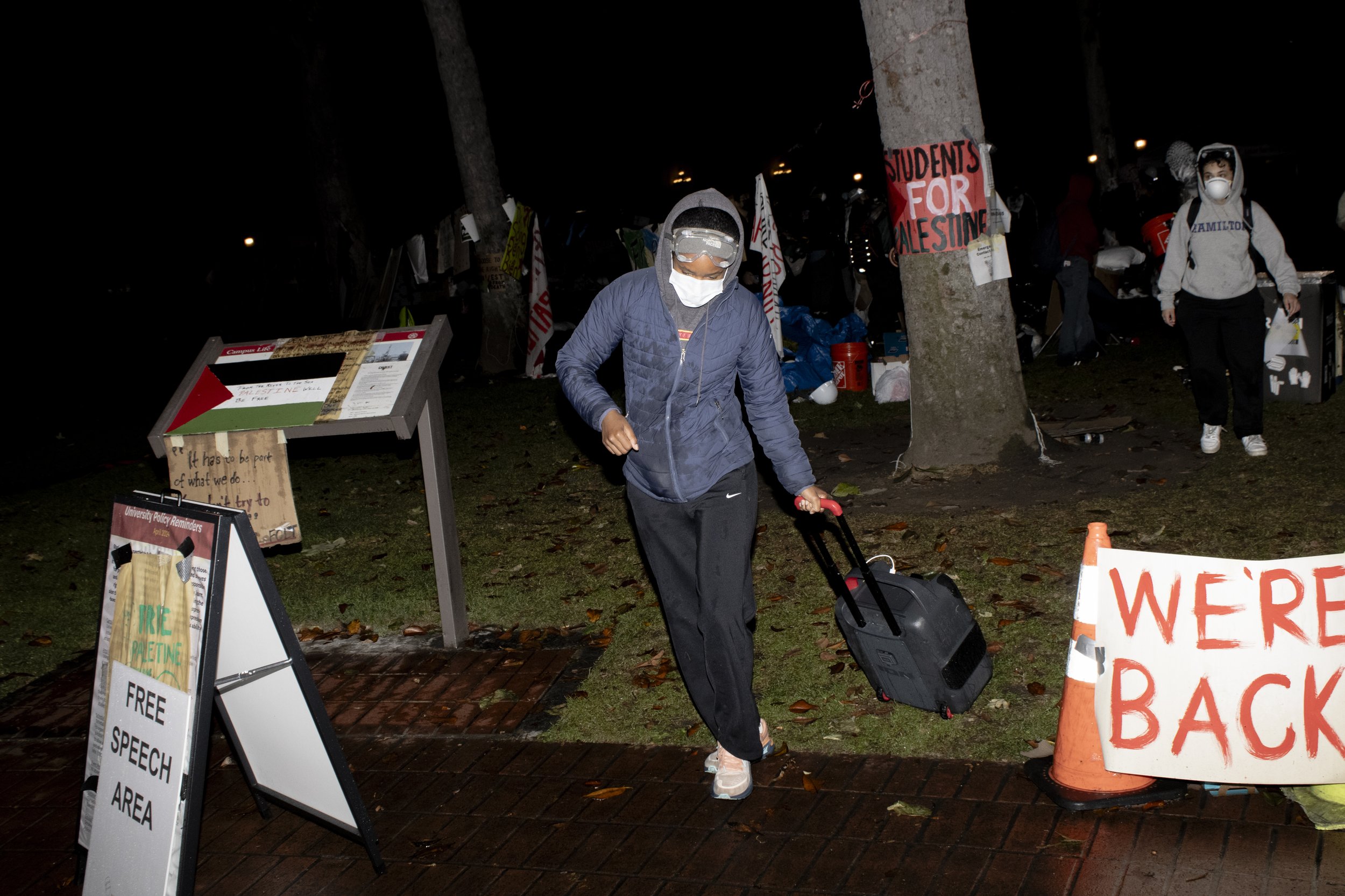  1.A protester from the University of Southern California Divest from Death coalition flees with supplies from their encampment after being told to disperse on Sunday, May 5, 2024, at The University of Southern California’s Alumni Park, in Los Angele