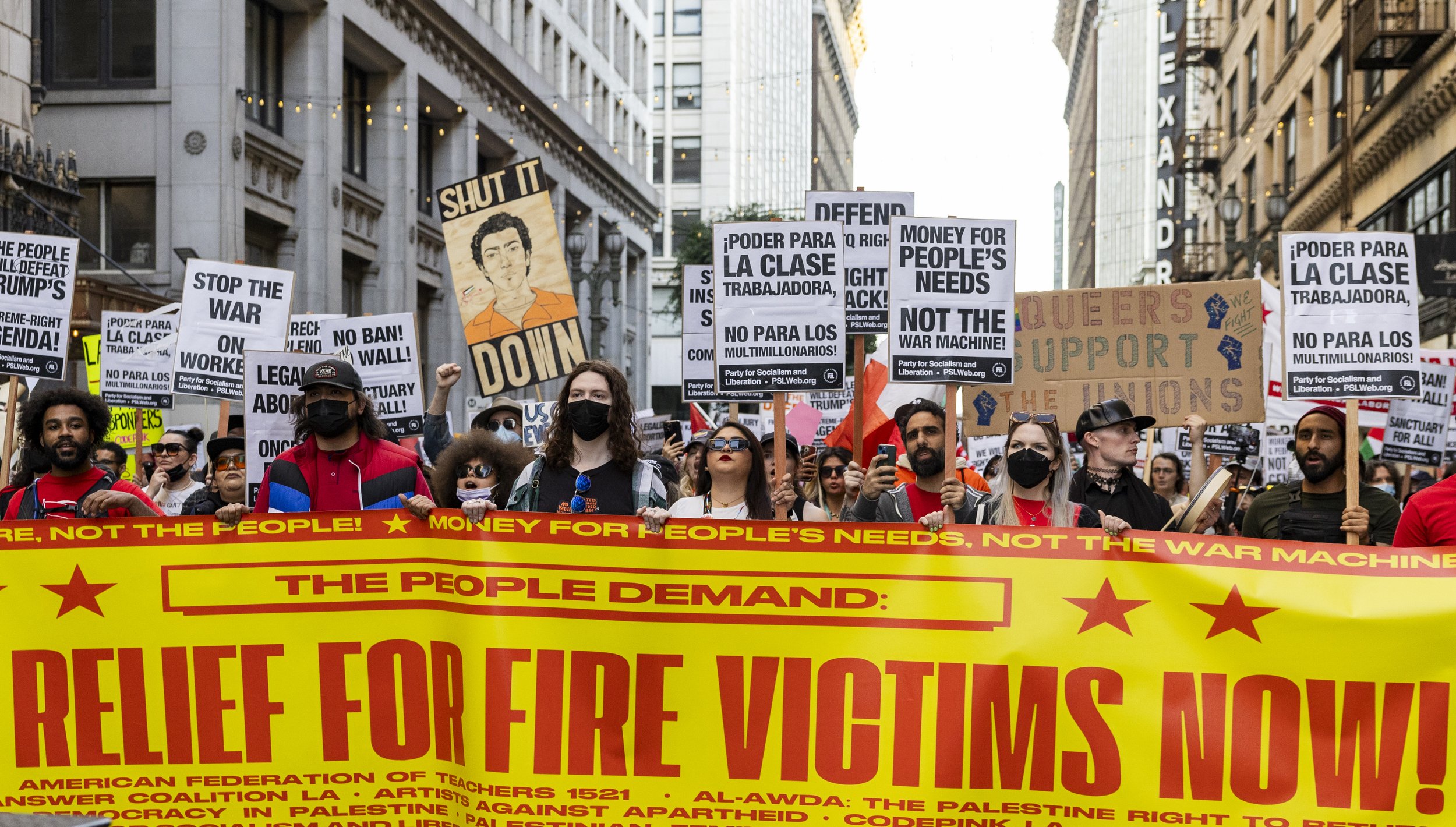 Protesters hold up a banner that states “Full Relief for Fire Victims Now!” while marching during the We Fight Back protest, with the message calling for the “defeat of Trump’s Extreme-Right Billionaire Agenda,” on Monday, January 20, 2025, in downt