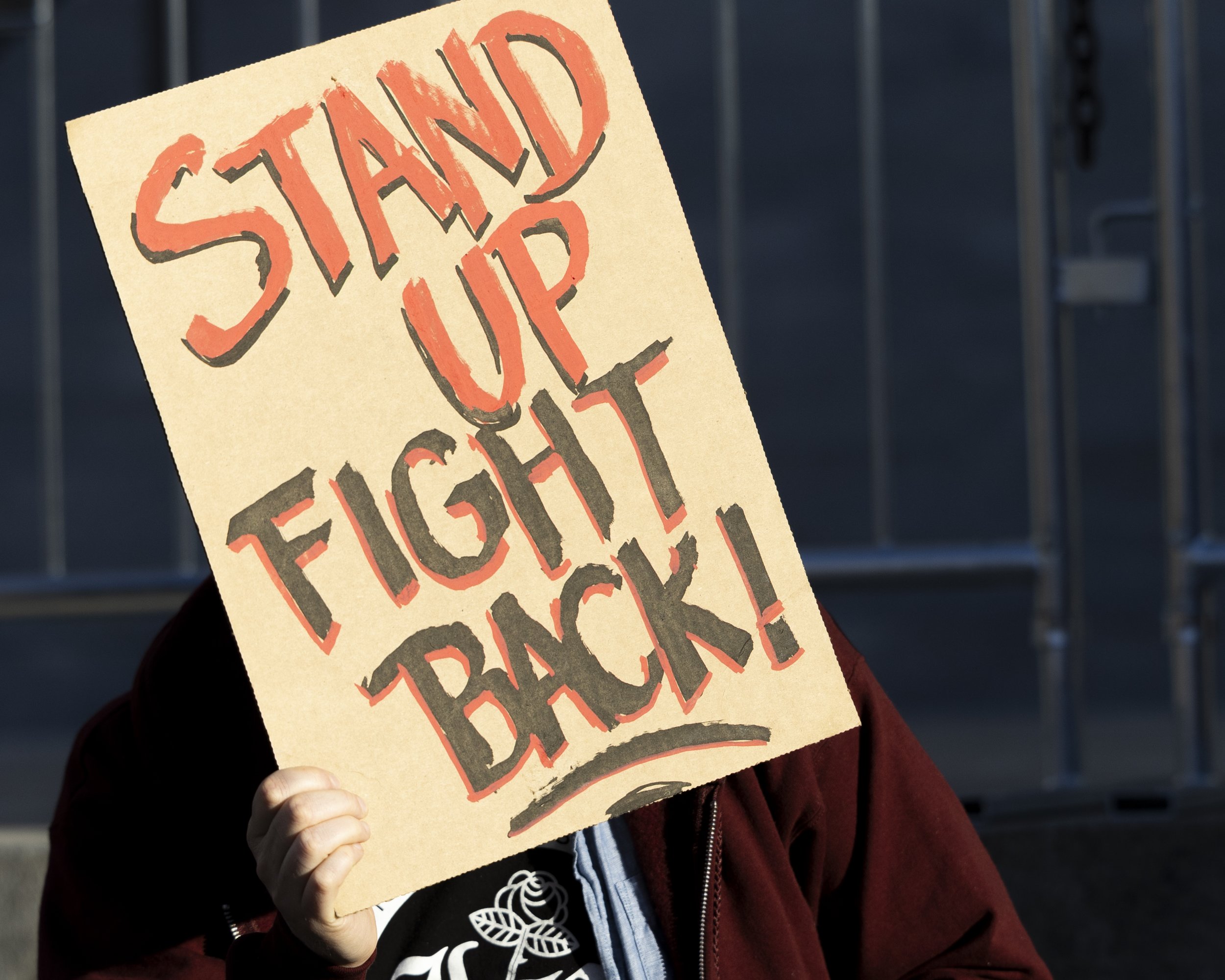 A protester holds a sign up that states, “Stand Up, Fight Back,” during the We Fight Back protest with the message of calling for the “defeat of Trump’s Extreme-Right Billionaire Agenda,” on Monday, January 20, 2025, at City Hall in downtown Los Ang