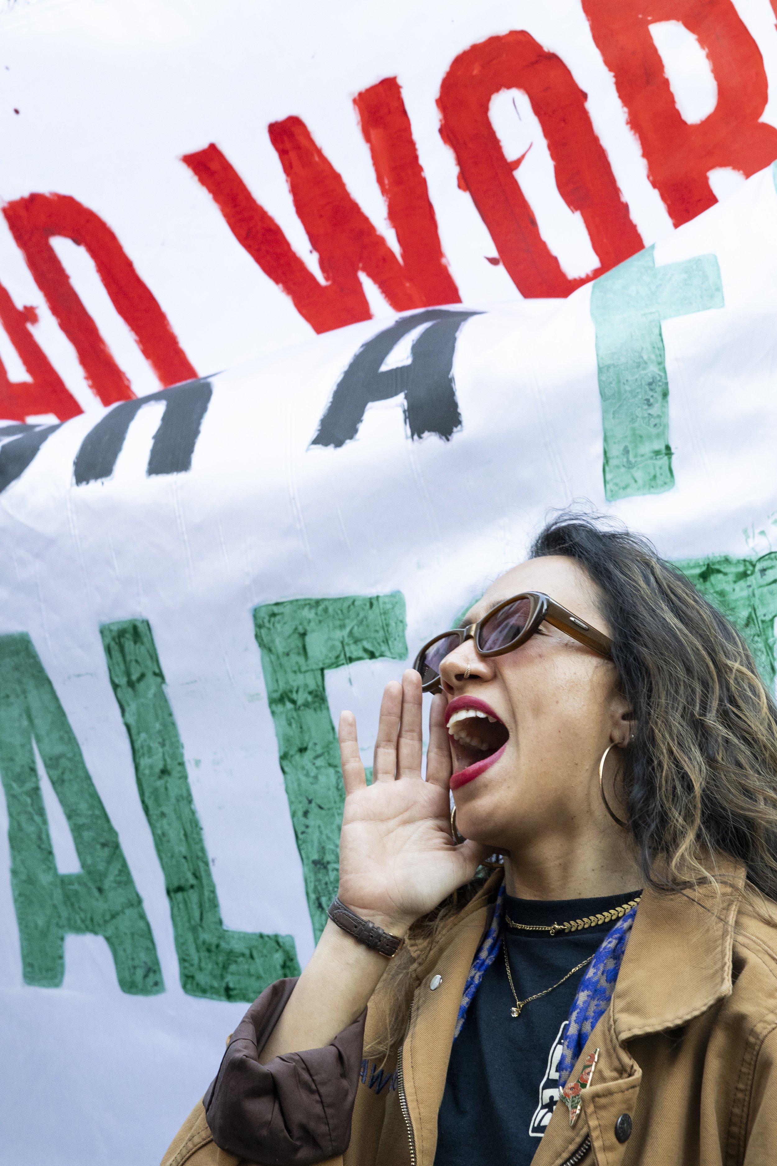 A protester chants in front of a flag that states “Grad workers for a free Palestine” with a USC graduate student worker organization committee logo during the We Fight Back protest with the message of calling for the “defeat of Trump’s Extreme-Righ