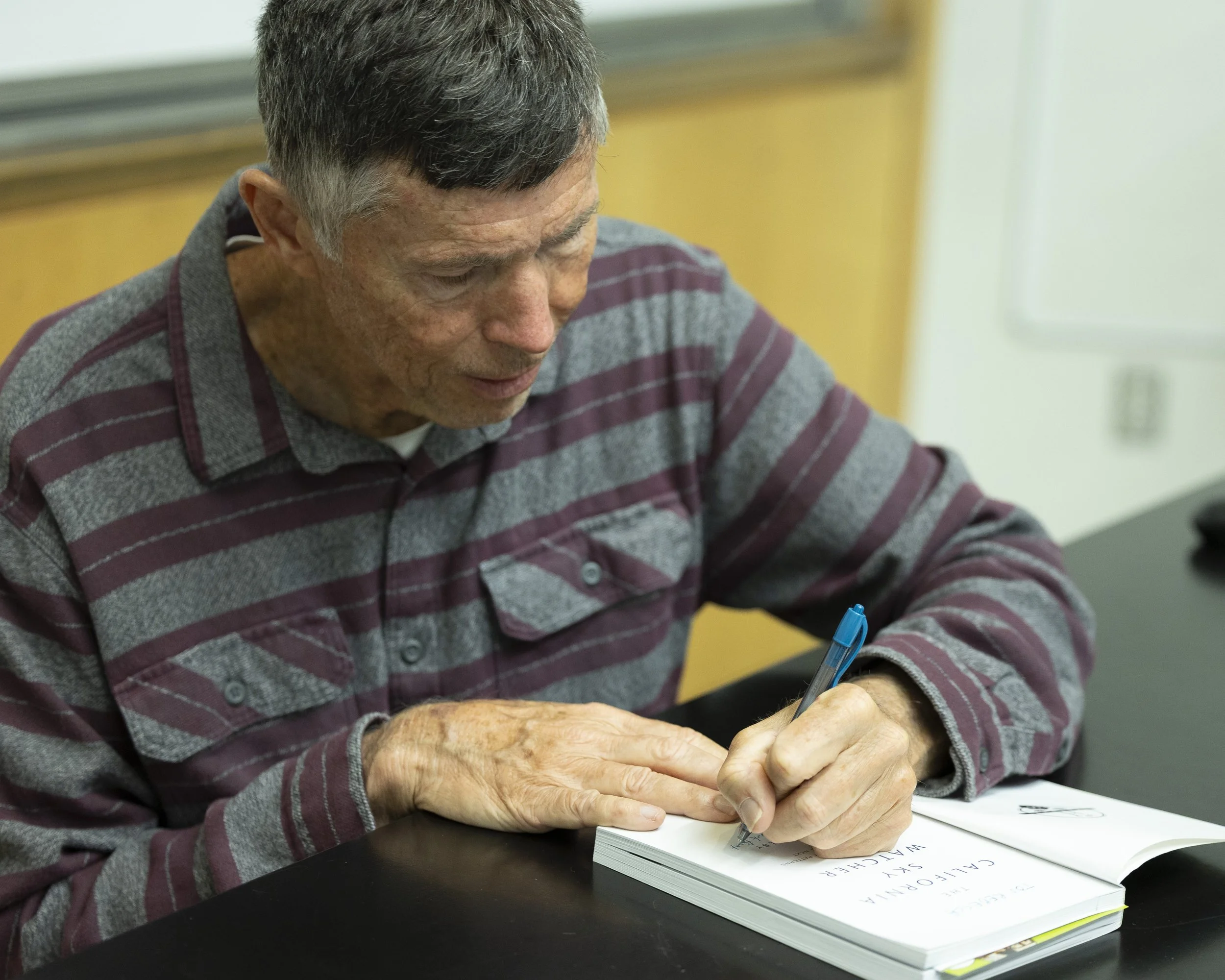  William Selby, age 71, a retired Santa Monica College (SMC) geography professor and author of his latest book ‘The California’s Sky Watcher: Understanding Weather Patterns and What Comes Next’, signs his book for a former student (1987) and now work