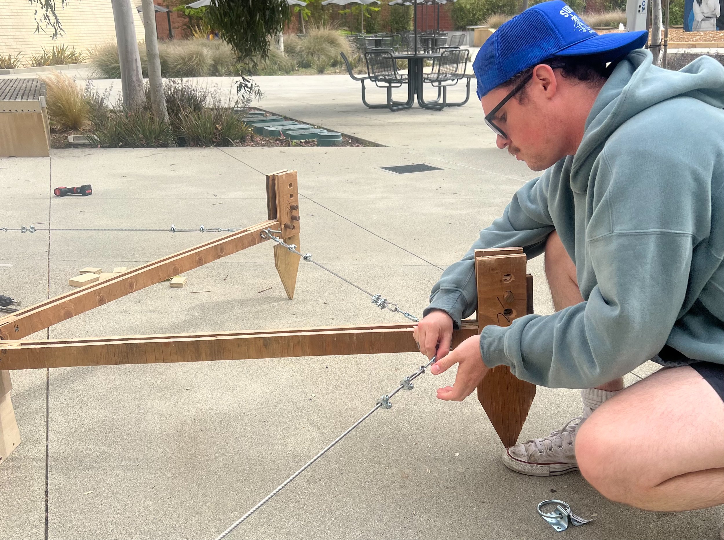 Beau Carter, a second-year architecture student at Santa Monica College (SMC) and lead designer for "Team Tentsion", tightens a turnbuckle to secure a tension cable on a structural element during preparations for the Design Village Competition at th