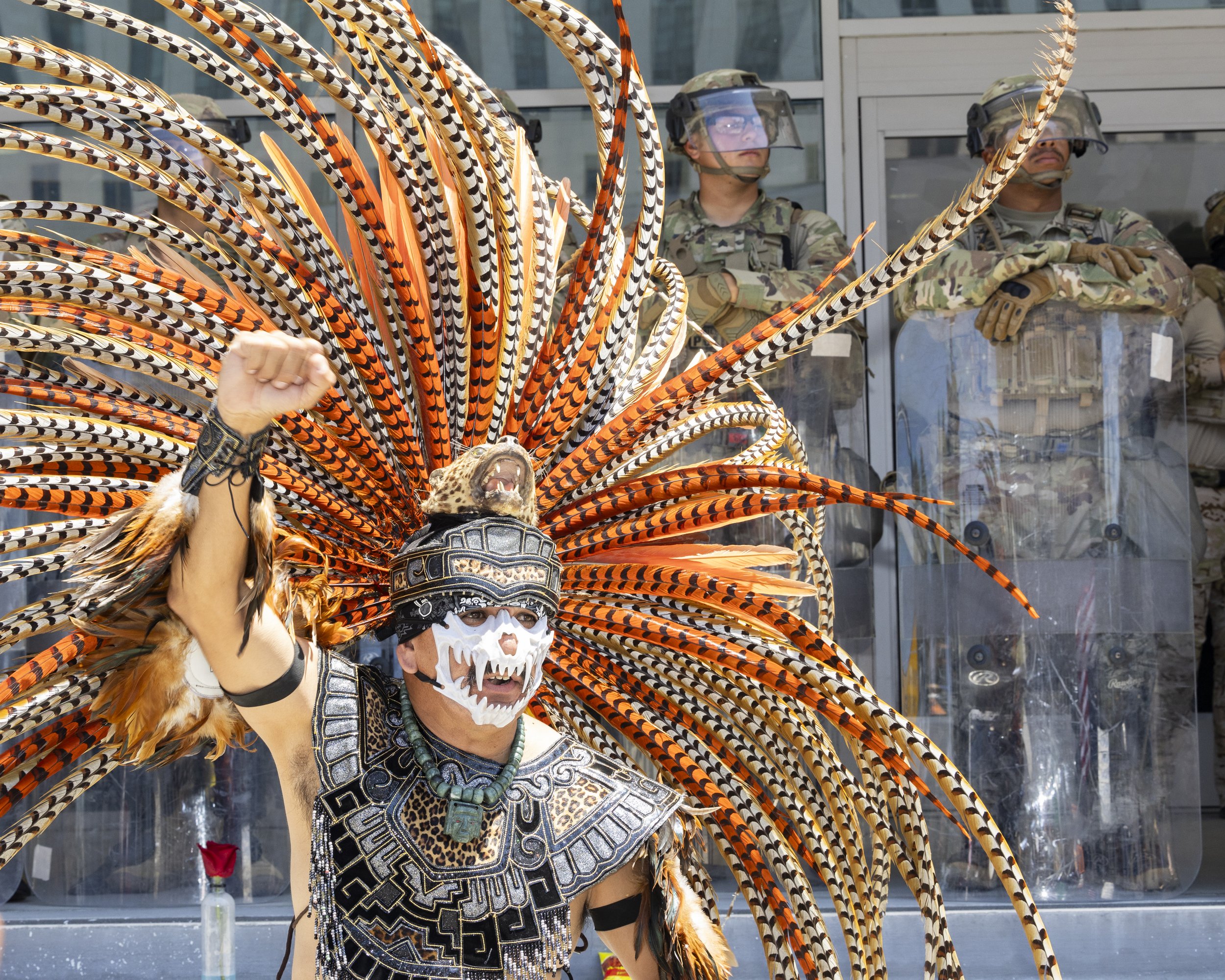 A protester dressed in a traditional Native American ceremonial outfit pumps his fist in front of Marines guarding the Federal Building in Los Angeles, Calif., on Friday, July 4, 2025. 50501 SOCAL organized a protest called End The Occupation, criti