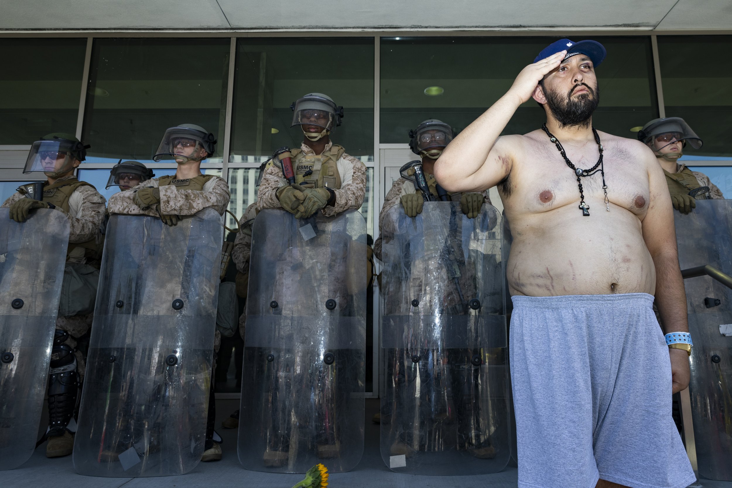 A protester salutes in front of Marines guarding the Federal Building in Los Angeles, Calif., on Friday, July 4, 2025. 50501 SOCAL organized a protest called End The Occupation, criticizing the Trump administration’s passing of the Big Beautiful Bil