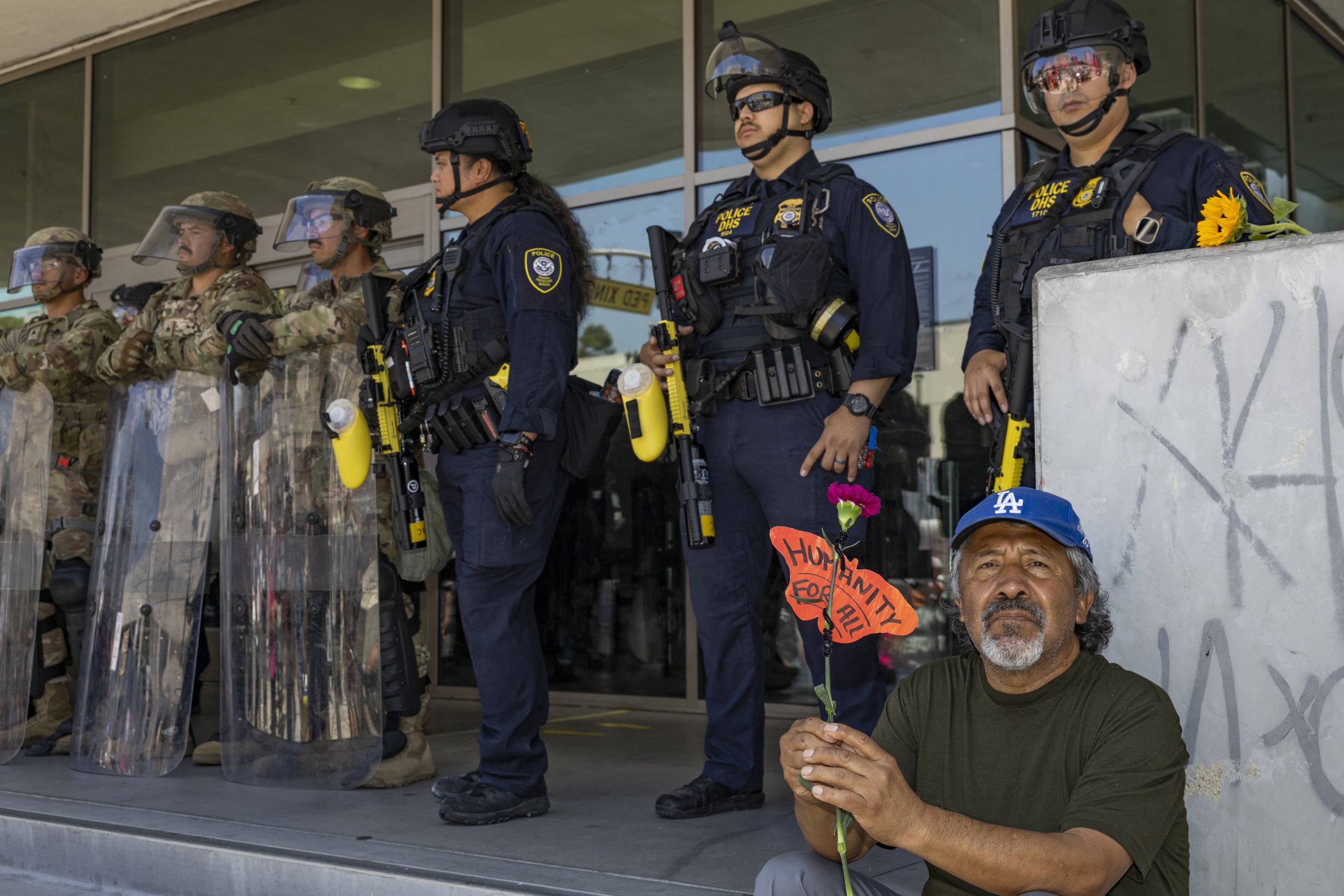 A protester holds a paper cutout of a butterfly that has humanity for all written on it in front of Marines guarding the Federal Building in Los Angeles, Calif., on Friday, July 4, 2025. 50501 SOCAL organized a protest called End The Occupation, cri