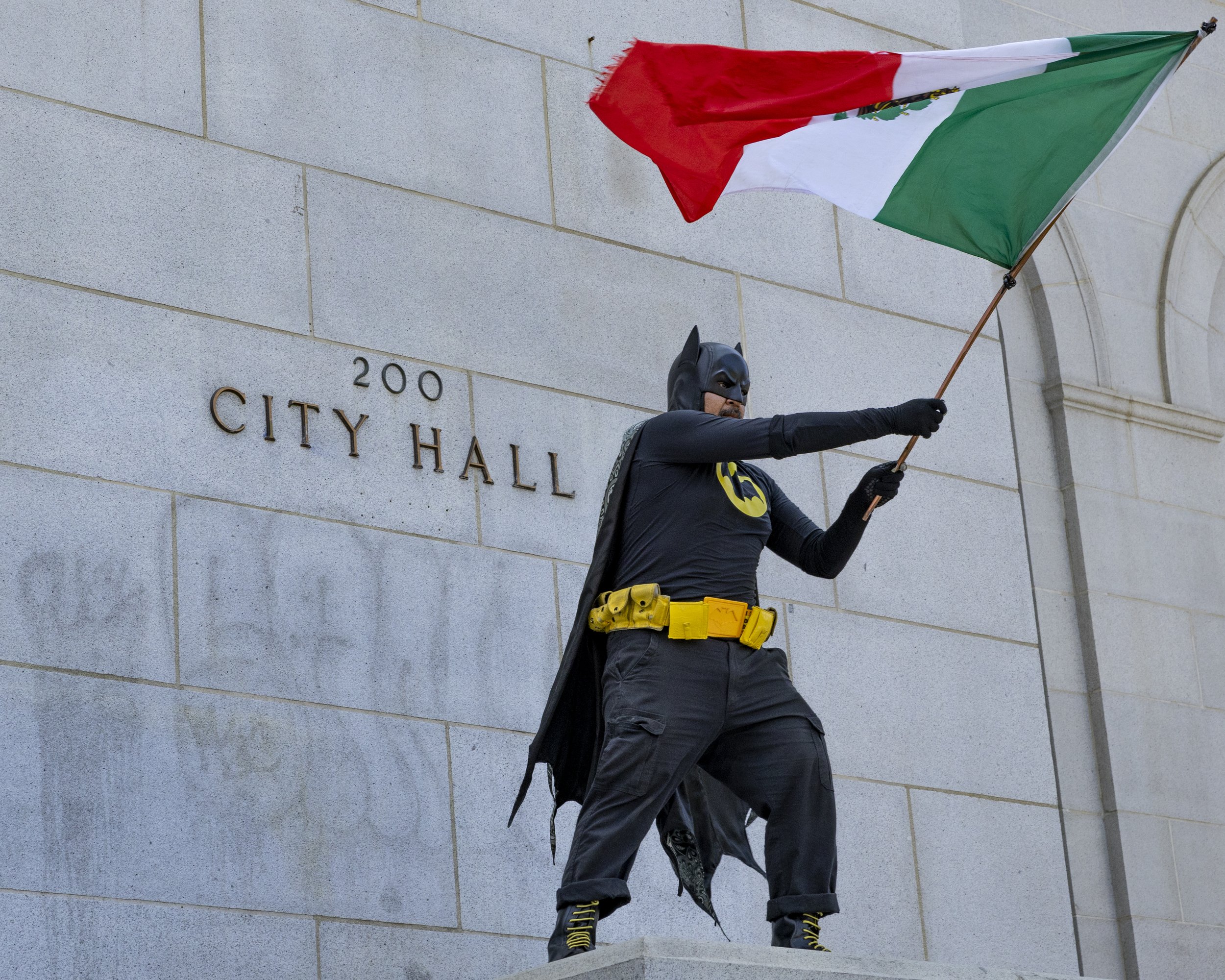 A man dressed as Batman waves a Mexican flag at City Hall in Los Angeles, Calif., on Friday, July 4, 2025. 50501 SOCAL organized a protest called End The Occupation, criticizing the Trump administration’s passing of the Big Beautiful Bill and callin