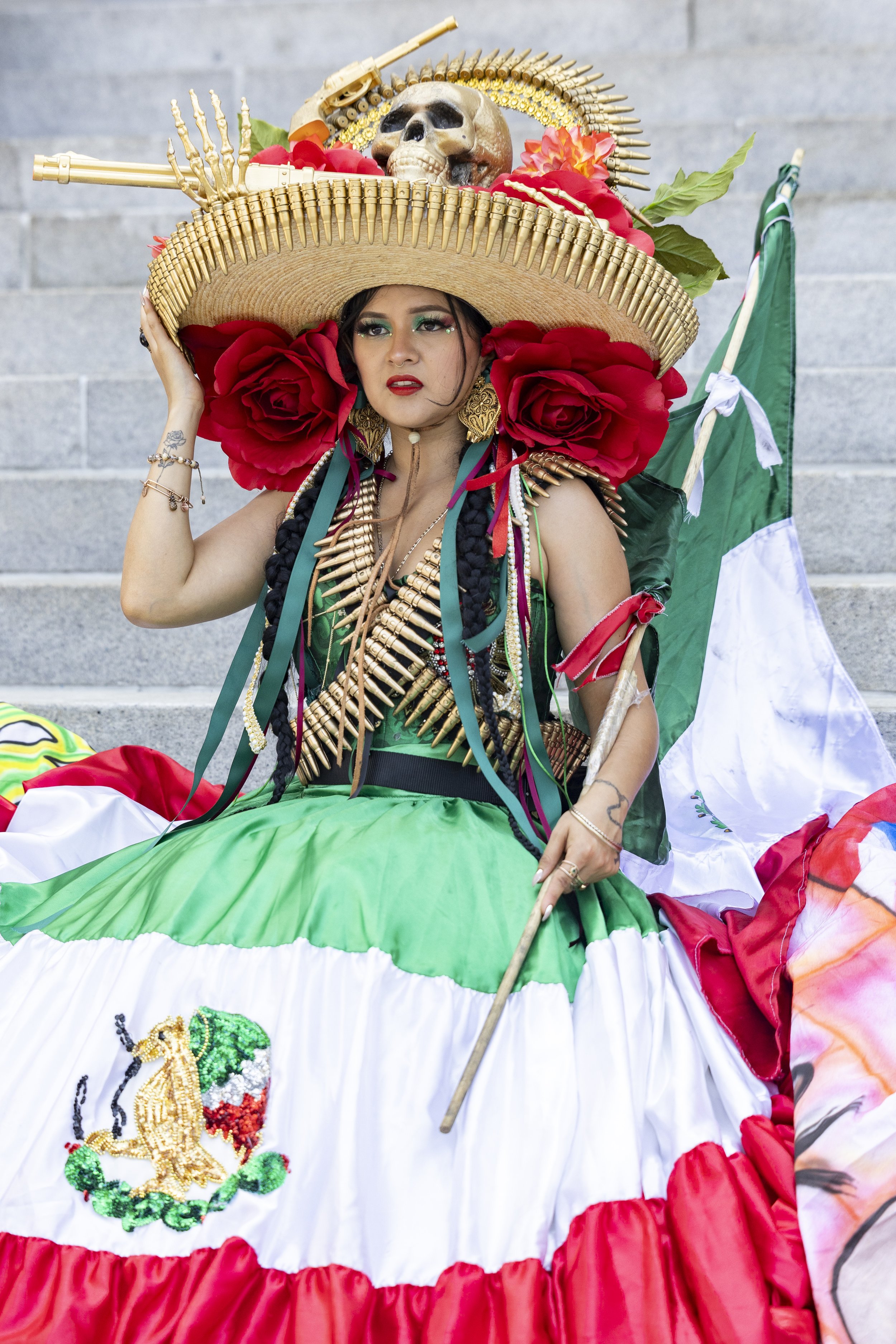 A protester dressed in a colorful dress sits on the stairs at City Hall in Los Angeles, Calif., on Friday, July 4, 2025. 50501 SOCAL organized a protest called End The Occupation, criticizing the Trump administration’s passing of the Big Beautiful B