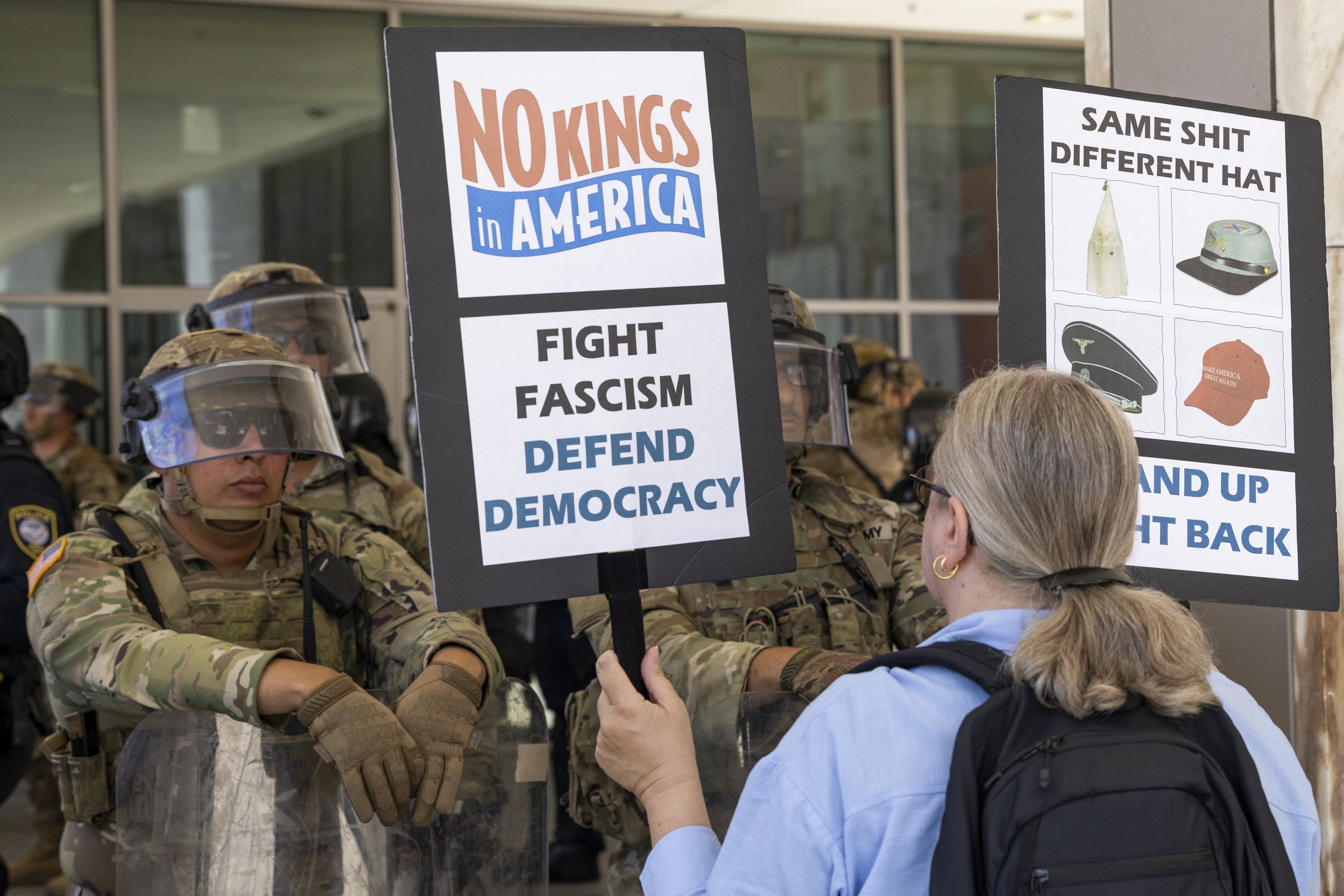A protester holds up signs to Marines guarding the Federal Building in Los Angeles, Calif., on Friday, July 4, 2025. 50501 SOCAL organized a protest called End The Occupation, criticizing the Trump administration’s passing of the Big Beautiful Bill
