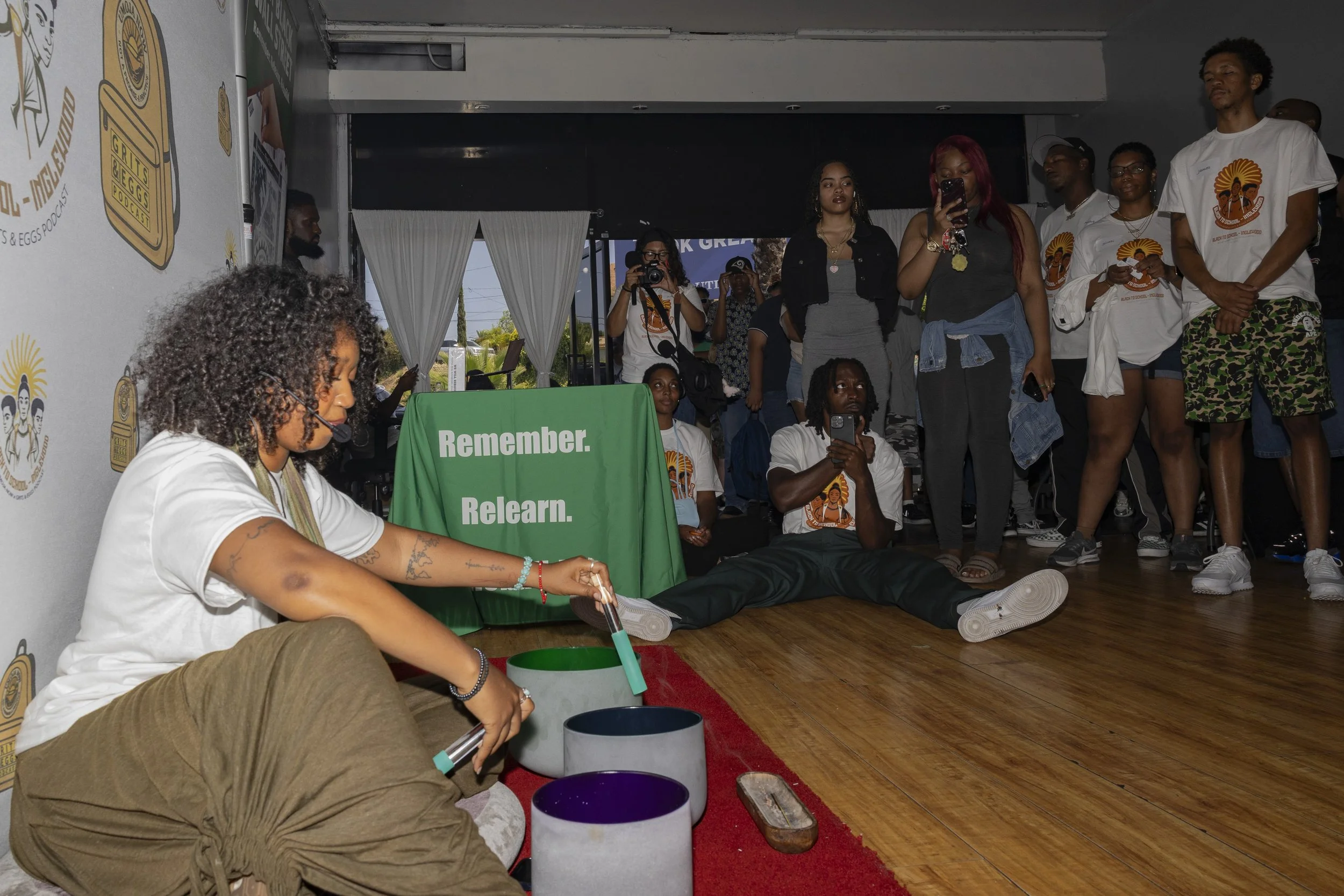 Justin Ellis-Brooks (Center) and Sirabi McIntyre (Far Right) watched a contributed soundbowl performance at their mutual aid event, “Black To School– Inglewood: Resouring Black Youth for the Road Ahead,” inside Event Space Inglewood in Inglewood, Ca