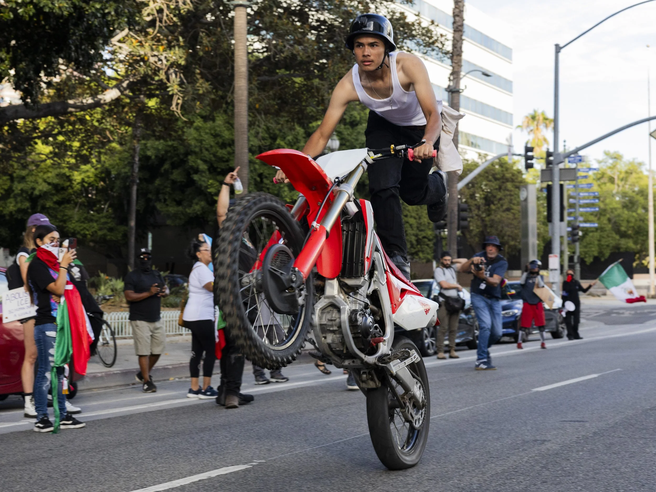 A dirt biker wheelies in front of the Los Angeles Police Department Headquarters on West First Street in Los Angeles, Calif., on Monday, Sept. 1, 2025, during a protest held on Labor Day organized by the activist group, ICE out of LA. ( Kayjel J. Ma