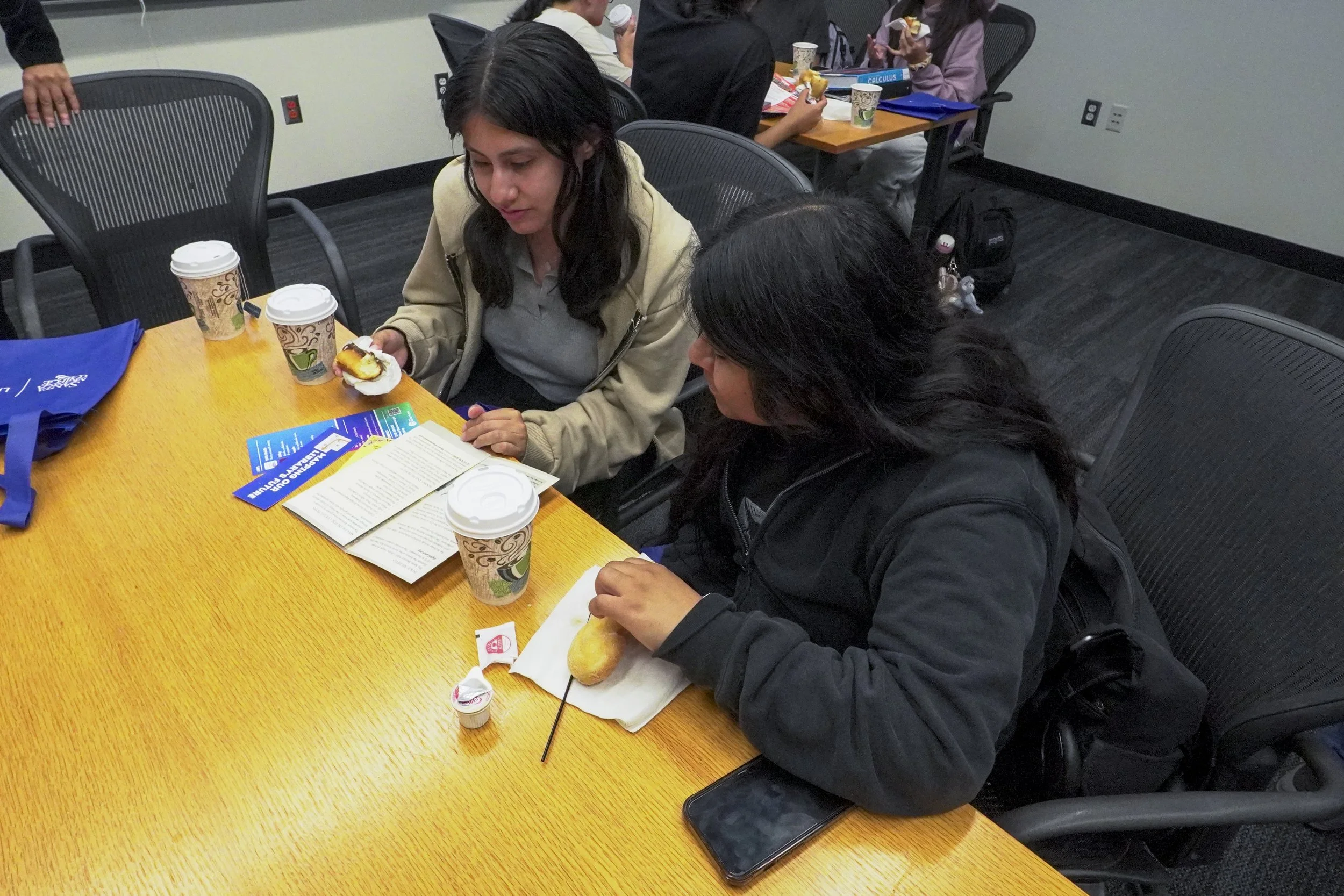 Daniela Elias (left), and Montserrat Sanchez (right) Santa Monica College (SMC) students read over pamphlets provided by the Santa Monica Public Library at the Coffee with Librarians event on Thursday, Sept. 18, 2025 at SMC, in Santa Monica, Calif.