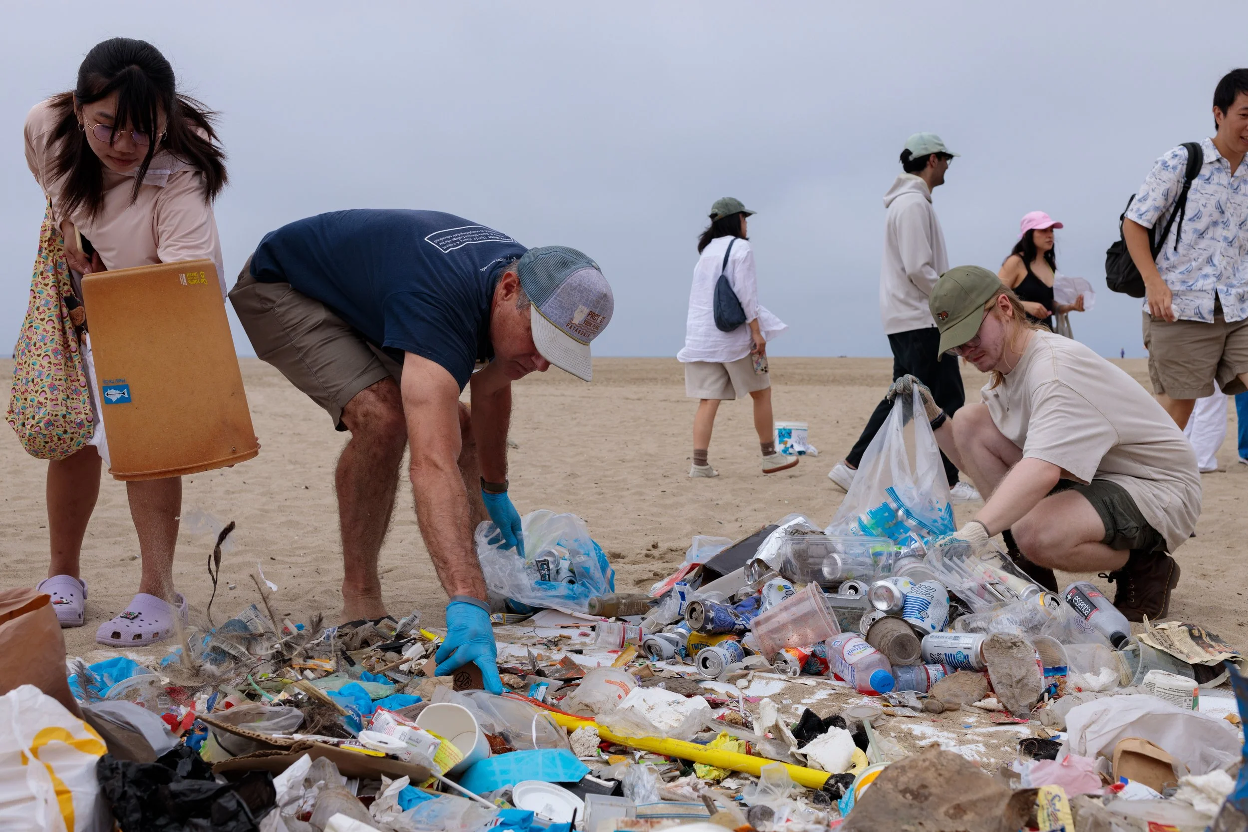 Ferris Kawar (center), Sustainability Project Manager at Santa Monica College, and Miles Bunell (R) sort trash from recycling while a volunteer (L) dumps out her bucket at the 36th annual Coastal Cleanup Day on Saturday Sept. 20, 2025 in Santa Monic