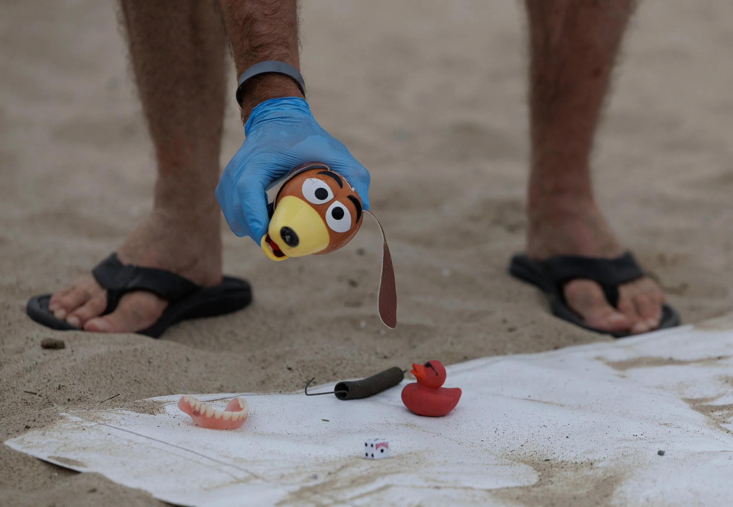 Ferris Kawar, Sustainability Project Manager at Santa Monica College, picks up eccentric found trash items placed on the corner of the collection tarp at the 36th annual Coastal Cleanup Day on Saturday Sept. 20, 2025 in Santa Monica, Calif. Coastal