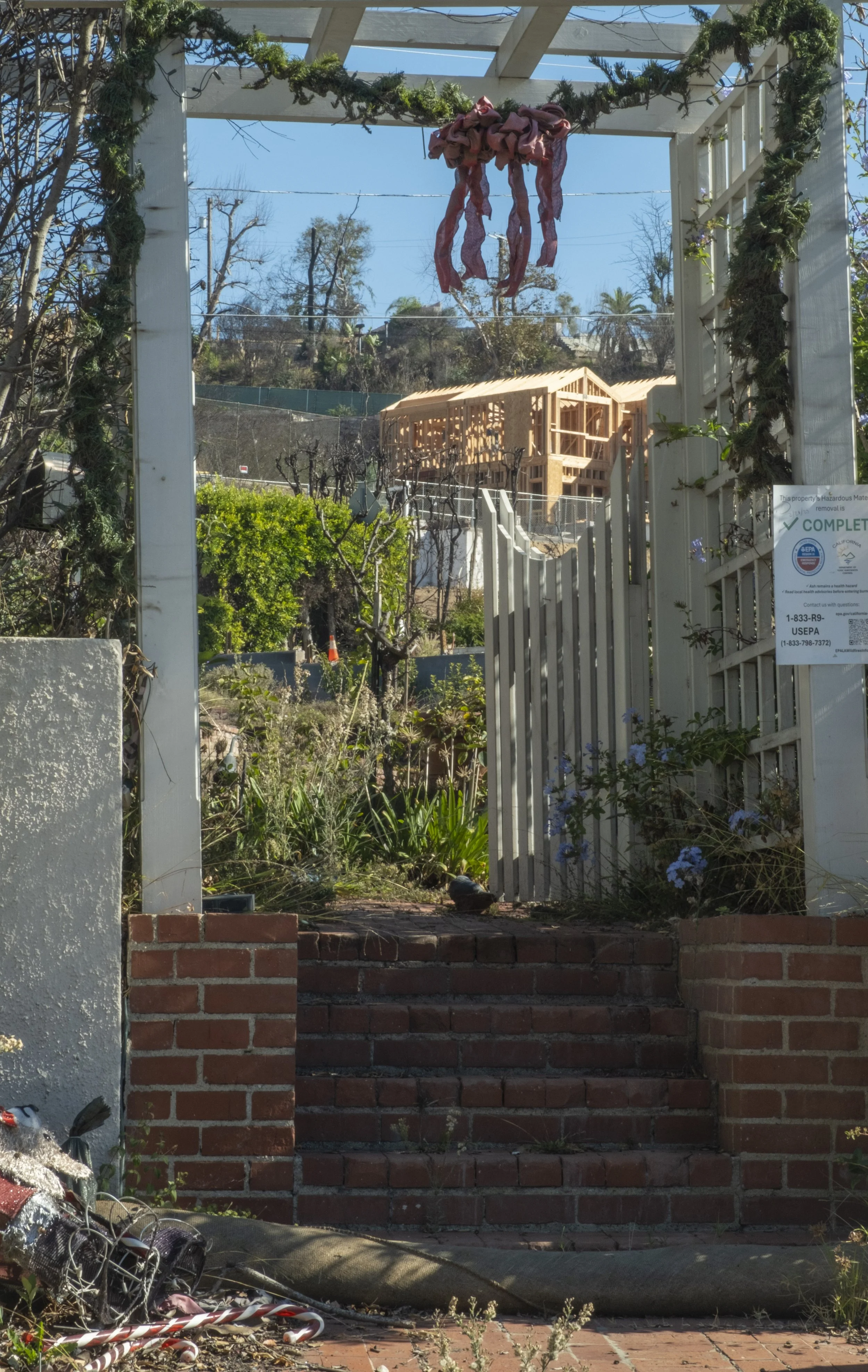  A house frame under construction can be seen behind a lot whose entryway is adorned with Christmas decorations on Friday, Oct. 17, 2025, in Pacific Palisades neighborhood of Los Angeles, Calif. After eight months of debris cleanup, residents are beg