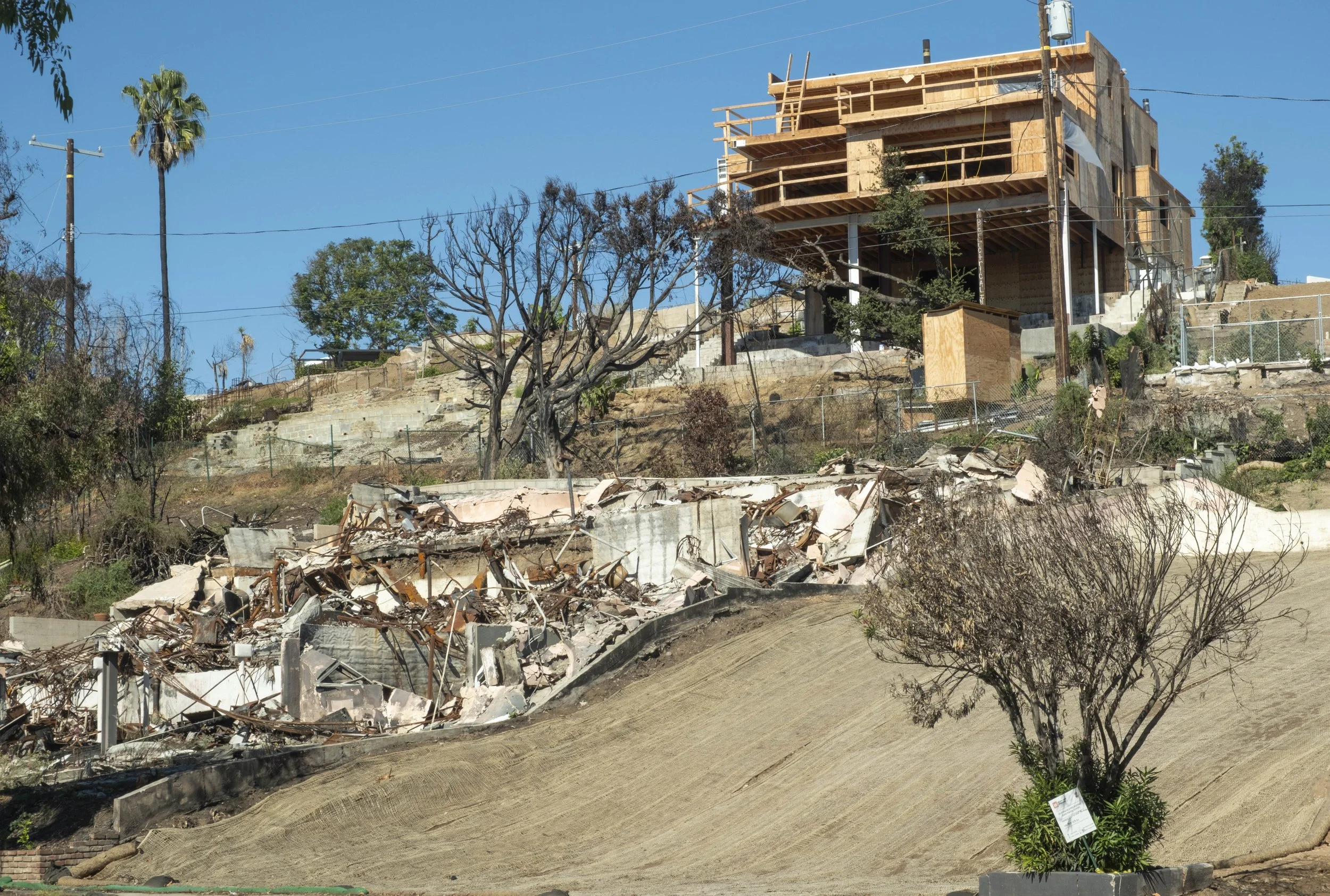  A house frame under construction sits on top of a hill where the lot below still requires debris removal, on Friday, Oct. 17, 2025, in Pacific Palisades neighborhood of Los Angeles, Calif. After eight months of debris cleanup, residents are beginnin