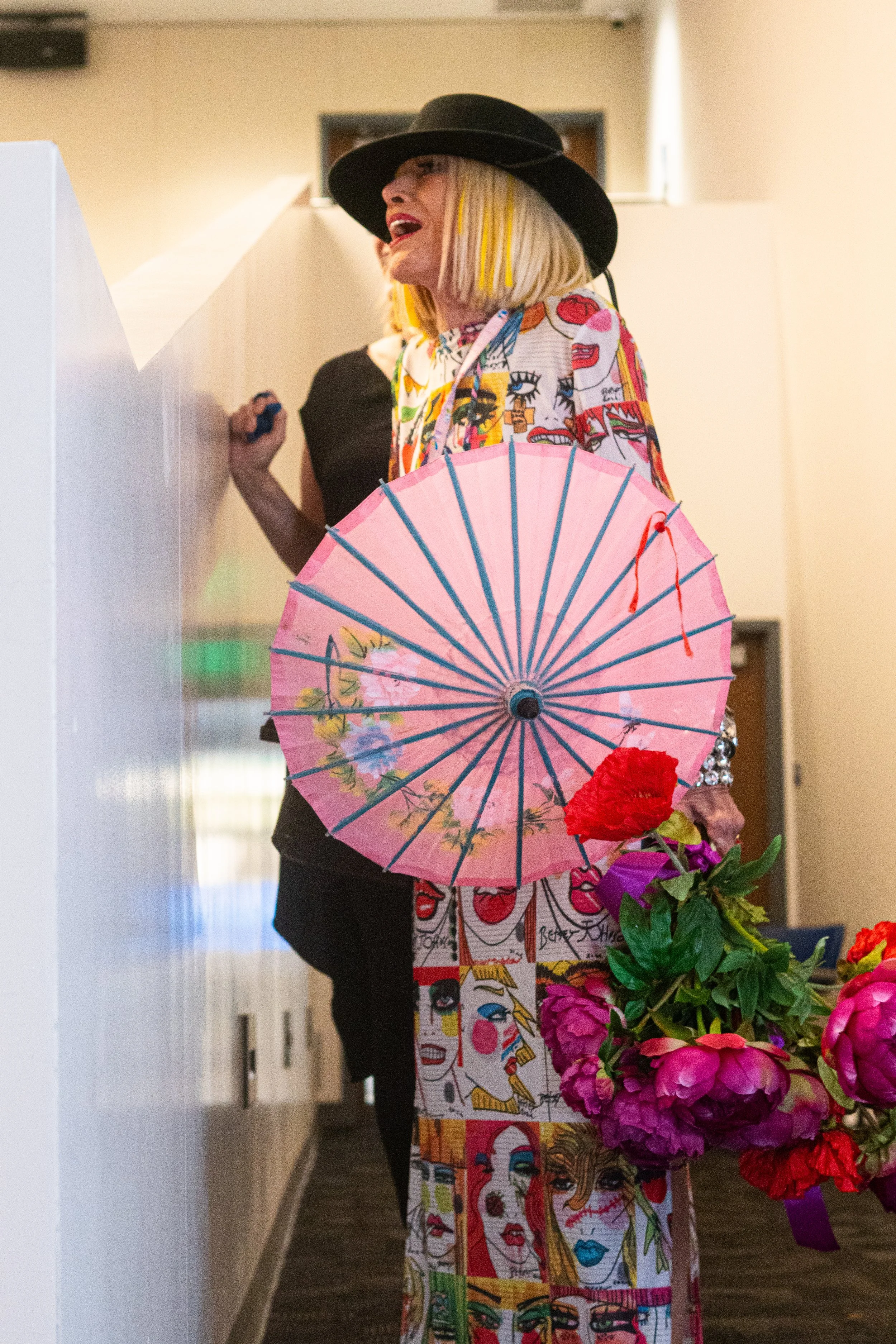  Fashion designer Betsey Johnson carries an umbrella and flowers shortly before she revisits the stage after changing her wardrobe halfway through her talk in the Student Services Center, Monday, Nov. 17, 2025, on the Santa Monica College (SMC) campu