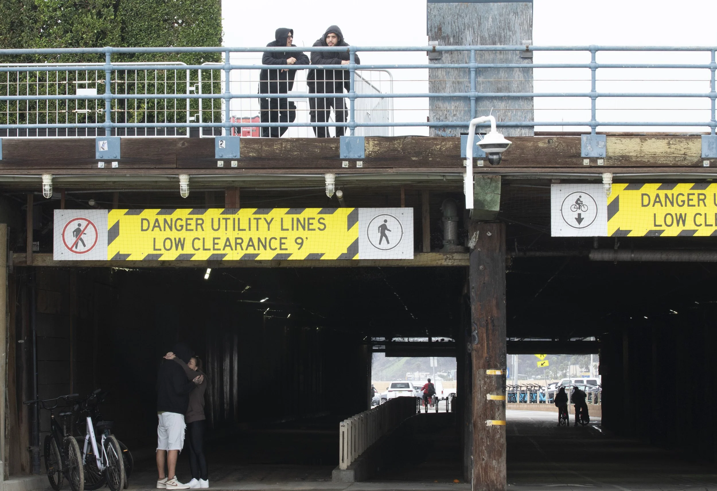  A couple embraces under the Santa Monica Pier while workers stand above on Monday, Nov. 17 at Santa Monica, Calif.  Heavy rain fell through the weekend and another storm is expected to arrive on Thursday, Nov. 20.  (Fai Fong | The Corsair) 