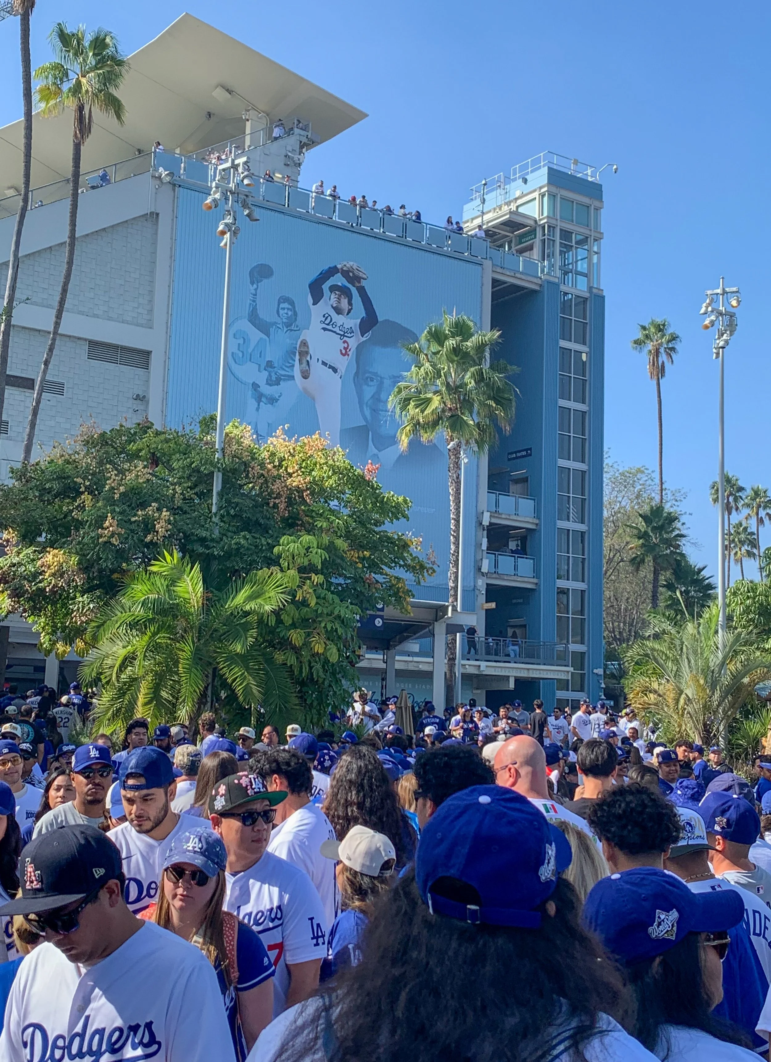 Dodger Fans walking down Left Field Plaza some getting food or drinks, others trying to get to their seats. A banner honoring pitcher Fernando Valenzuela as the walk by in Los Angeles, Calif., on Monday, Nov 3 2025, (Rafael Lopez | The Corsair) 