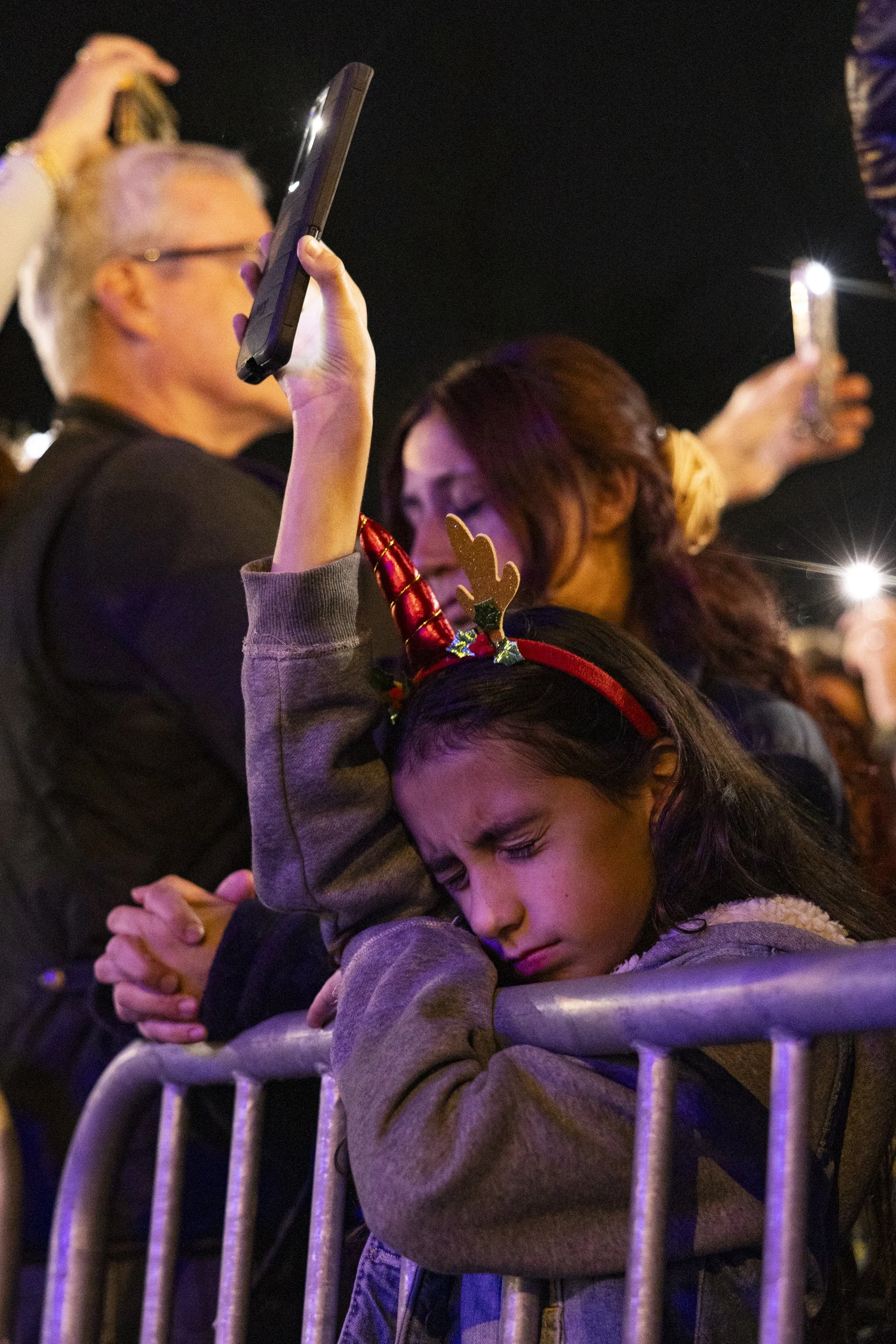  Community members raise their phones and take a minute and nineteen seconds of silence to honor the 19 victims who died in the Eaton Fire during the Christmas Tree Lane lighting ceremony in Altadena, Calif., on Saturday, Dec. 8, 2025, for the 105 an