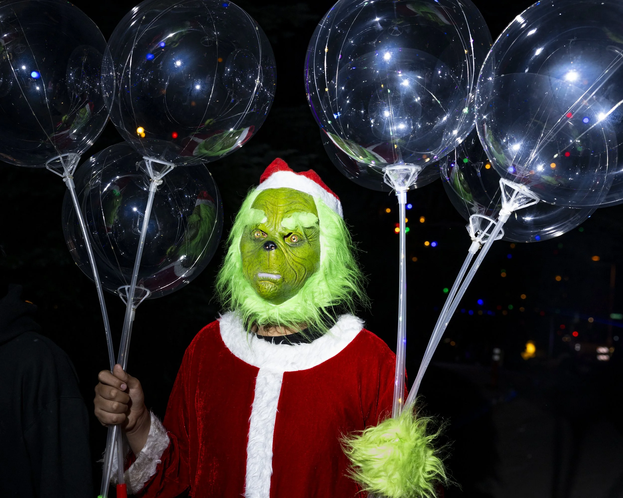  A person dressed in a Grinch costume sells balloons during the 105 Christmas Tree Lane lighting ceremony in Altadena, Calif., on Saturday, Dec. 8, 2025. A stretch of deodar cedar trees on Santa Rosa Boulevard is decorated with Christmas tree lights 