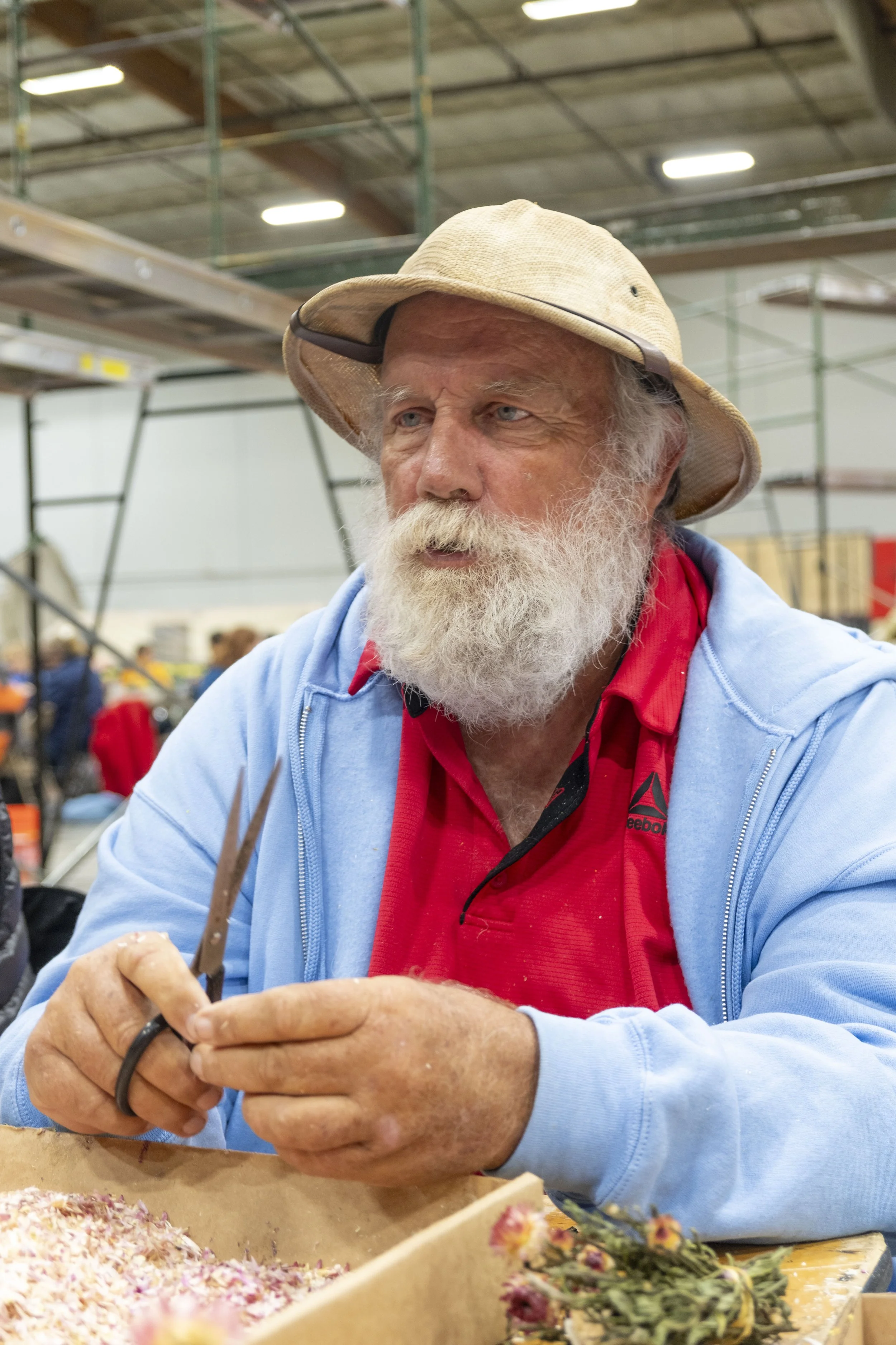 Ronnie Espolt of Apple Valley cuts flower petals to create covering material for a Rose Parade float on Friday, Dec. 26, 2025 at a warehouse in Irwindale, Calif.  Espolt has been decorating Rose Parade floats every year since 2009.  (The Corsair | F