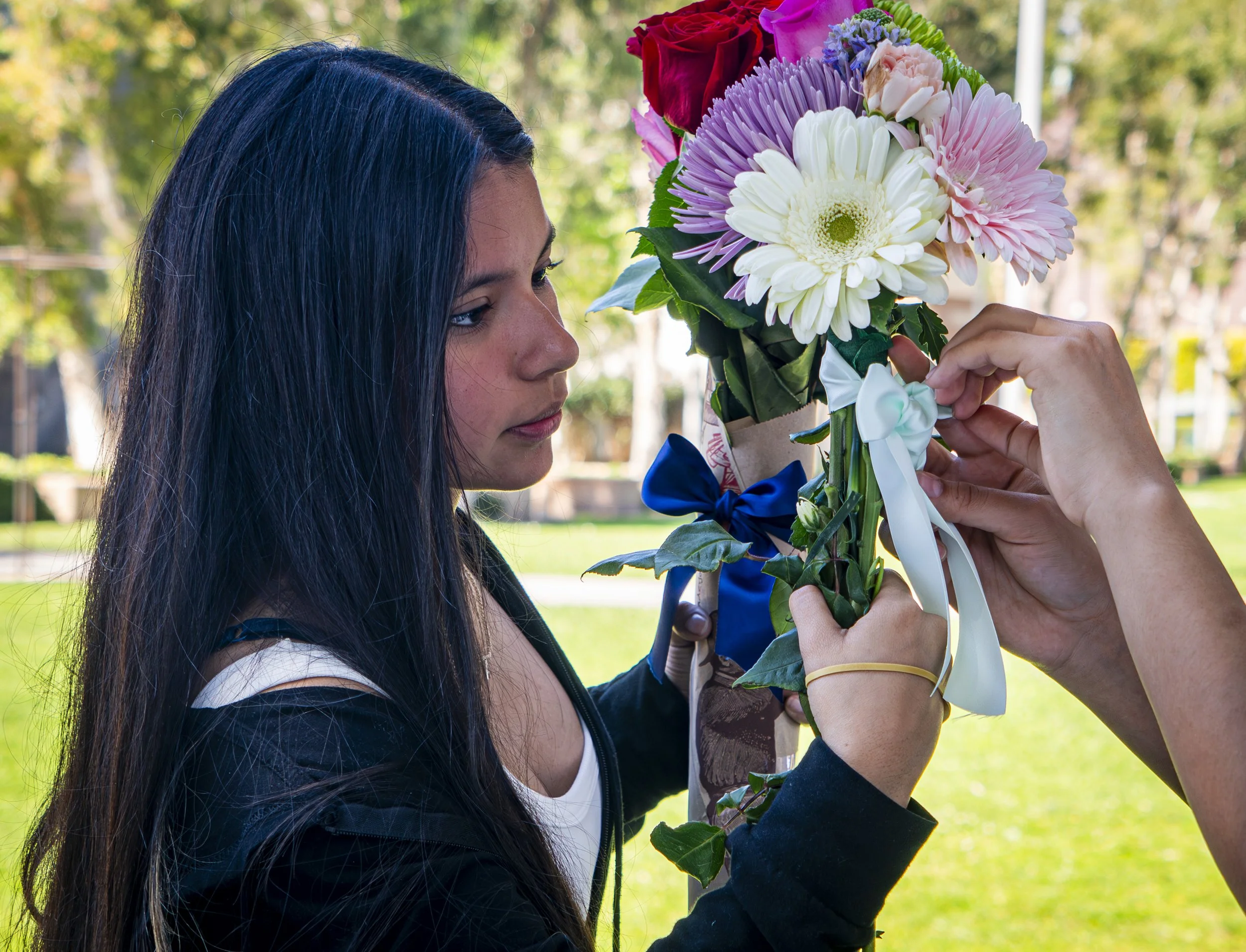  Santa Monica College Digital Marketing student Lia Bolanos holds flowers as she recieves help tying ribbons to hold arrangments in place  at the Associated Students Flower Market at Santa Monica College in Santa Monica, Calif., Thursday March. 19, 2
