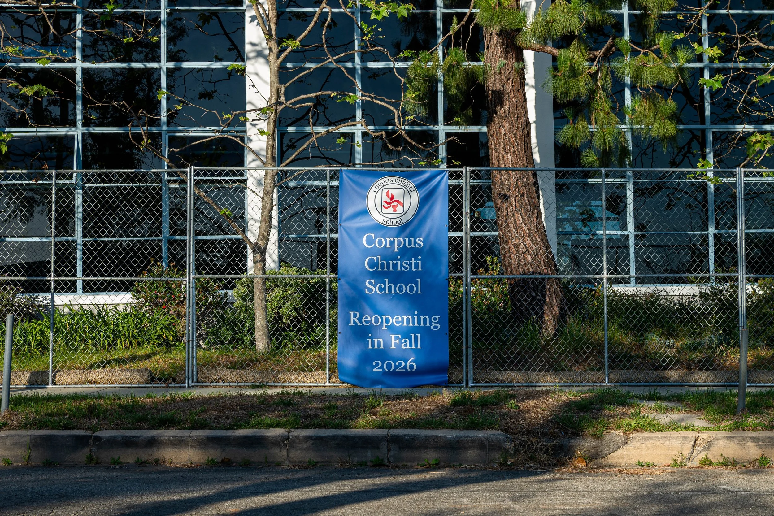  A banner hangs on a perimeter fence at the site of Corpus Christi Church announcing the upcoming reopening of the parish school, Monday, April 6, 2026, in Los Angeles, Calif. (Nathan Hanson | The Corsair) 