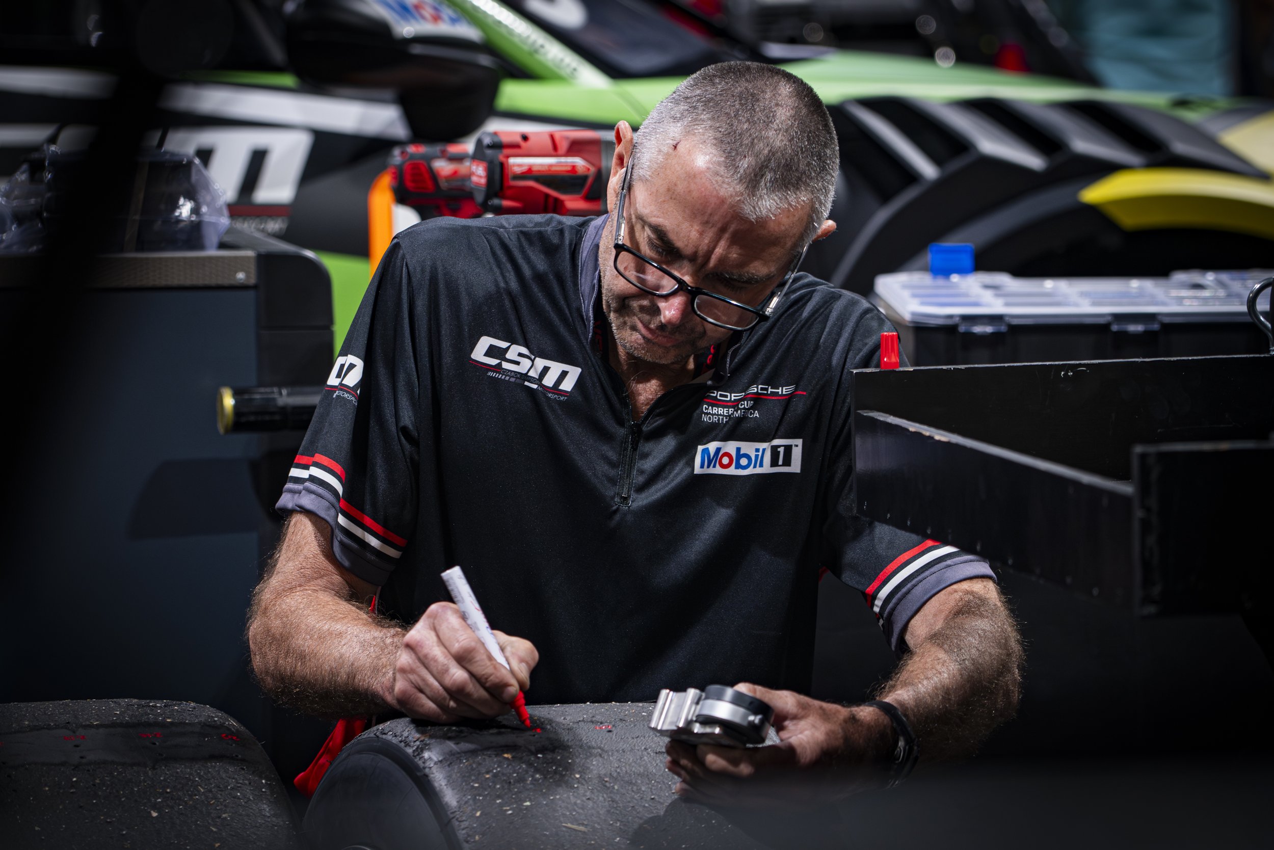  International Motor Sports Association (IMSA) Porsche Carrera Cup North America (PCCNA) series team Czabok-Simpson Motorsport (CSM) crew member inspects used tires for structural integrity, excessive wear, carcass damage, blistering, or delamination