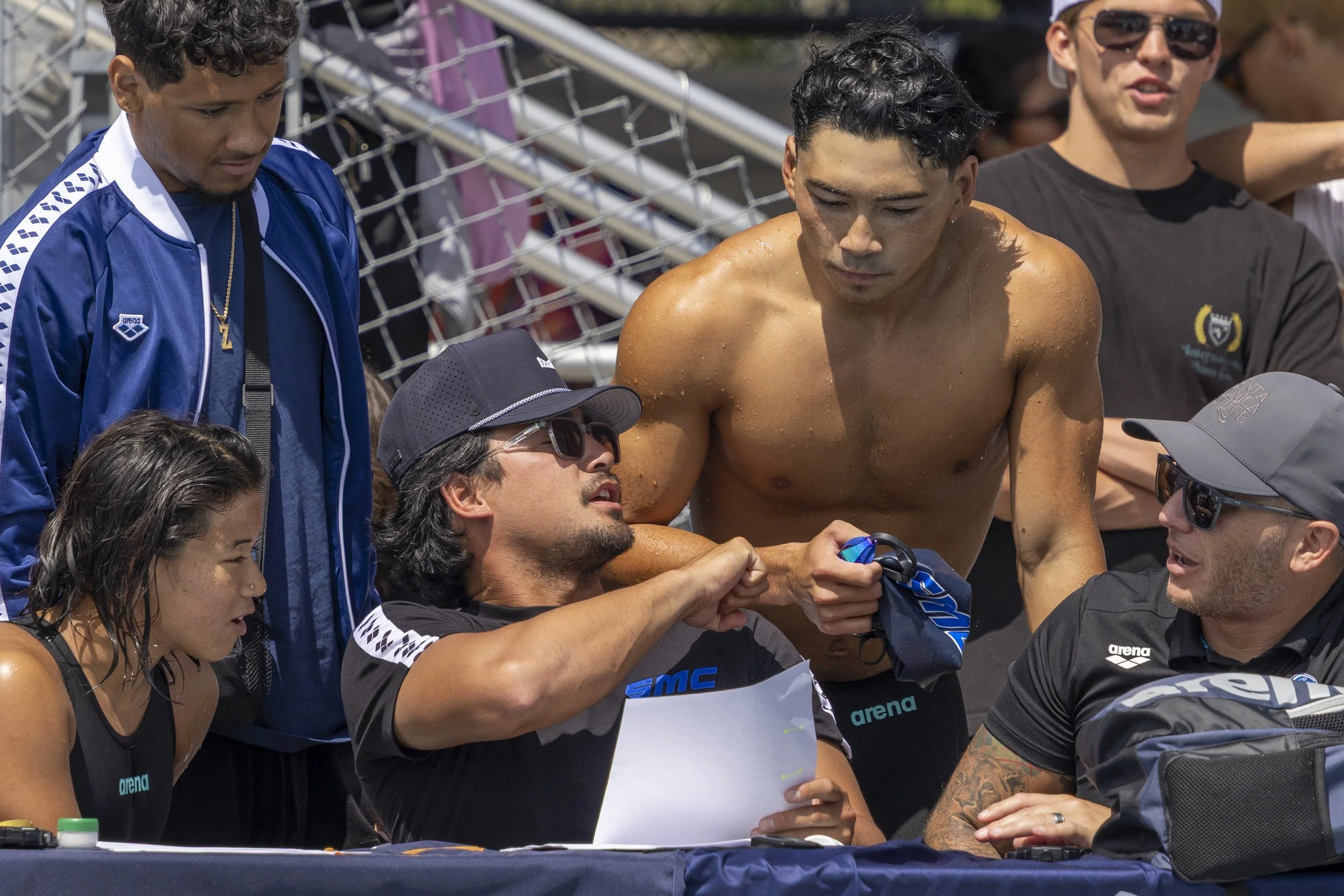  Santa Monica College (SMC) assistant coach J.J. Amis (center left) and his younger brother Riley Taizo Amis (center right) fist bump after Amis’ race in the 200m Individual Medley of the 3C2A State Championship alongside their team mates Corsair Izz