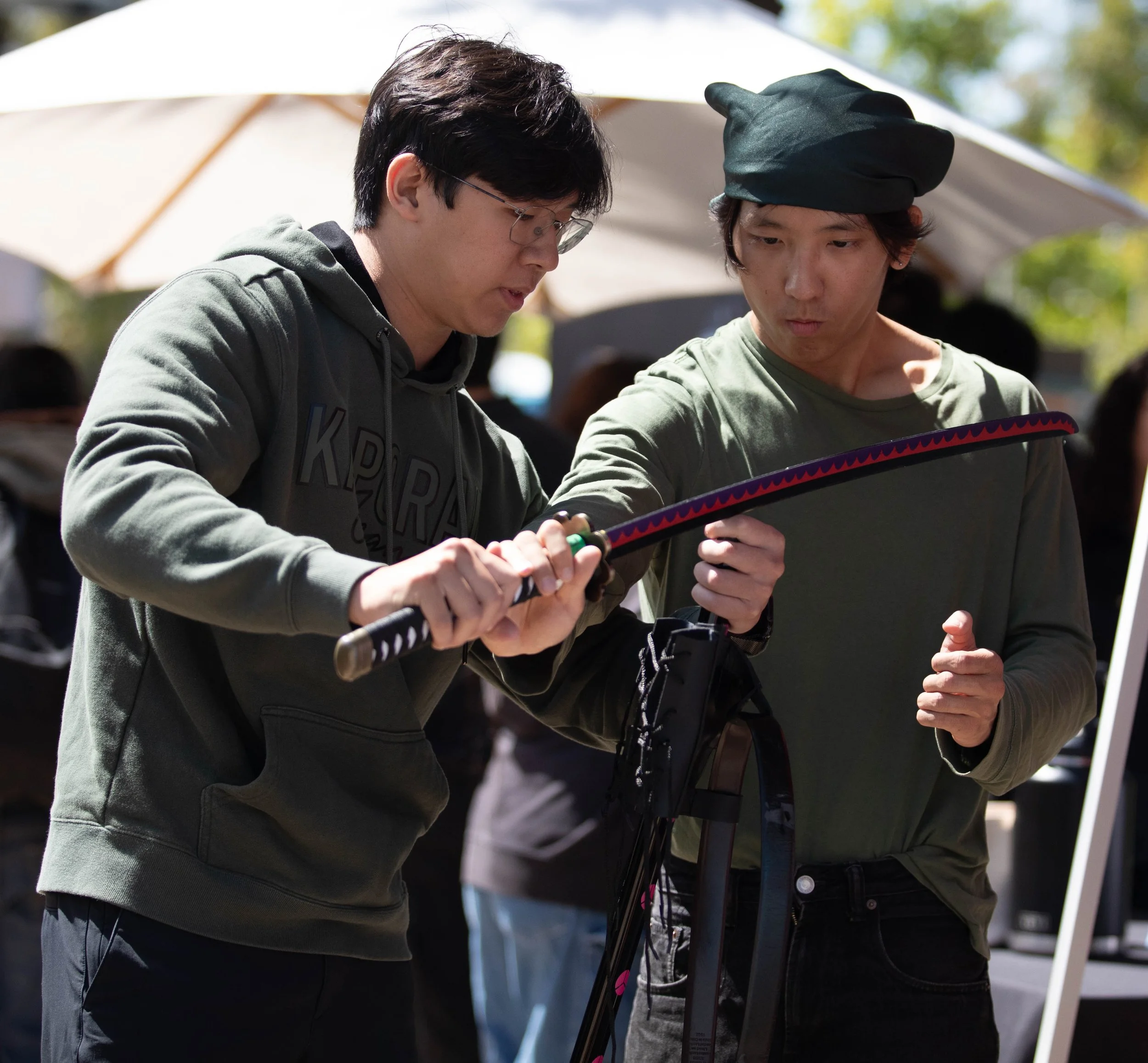  (L to R) Santa Monica College (SMC) sophomore and Business major Pawaret Patomworakul stops by the Corsair Game Jams table and lets SMC Business major and Corsair Game Jams club representative Joseph Ming show him a sword at the SMC fairy-tale theme