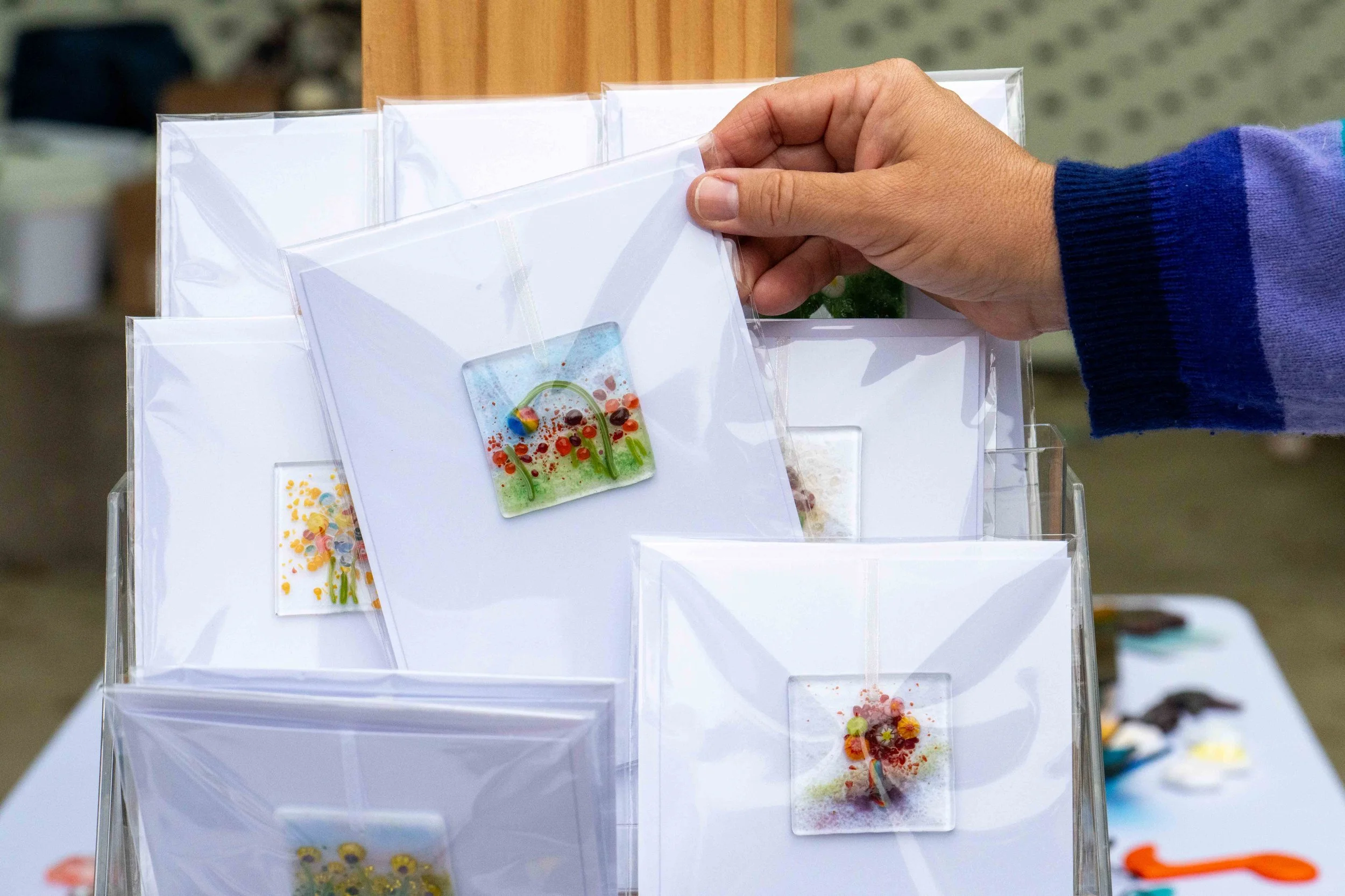  Santa Monica College (SMC) glass fusing artist Janet Zander holds one of her cards containing glass ornaments during SMC Art Department's Mother's Day Glass Sale at Virginia Park Farmers Market in Santa Monica, Calif., Saturday, May 2, 2026. The gla