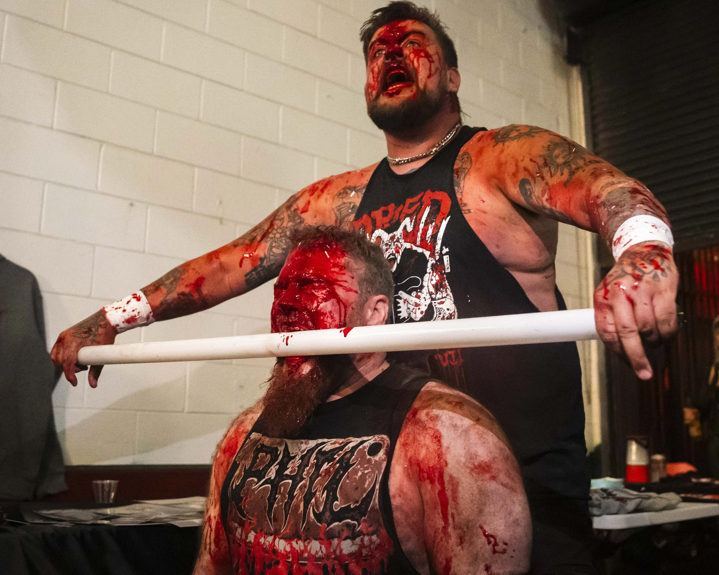  Deathmatch wrestler Phil Insane (L) bites into a glass tube that Joe Dred (R) placed in his mouth on Saturday, May 16, 2026, during a match inside the LA Church in Los Angeles. (Kayjel J. Mairena | The Corsair) 