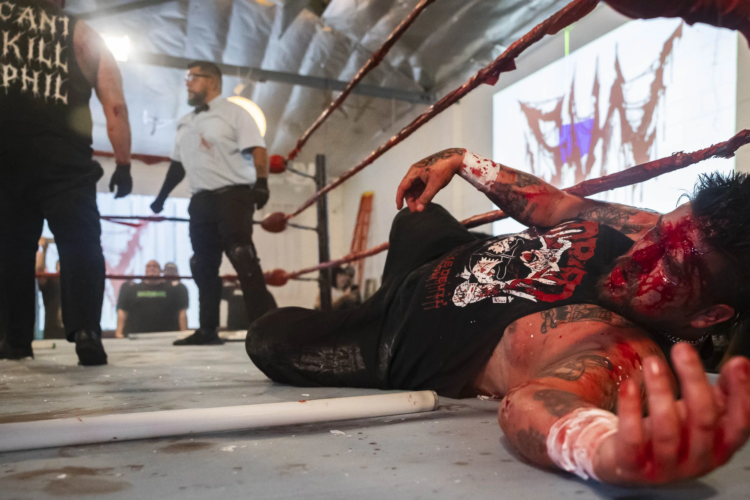  Deathmatch wrestler Phil Insane (L) turns towards referee Mike Valencia (C) after dropping Joe Dred (R) with a bundle of light tubes during a match inside the LA Church in Los Angeles on Saturday, May 16, 2026. (Kayjel J. Mairena | The Corsair) 