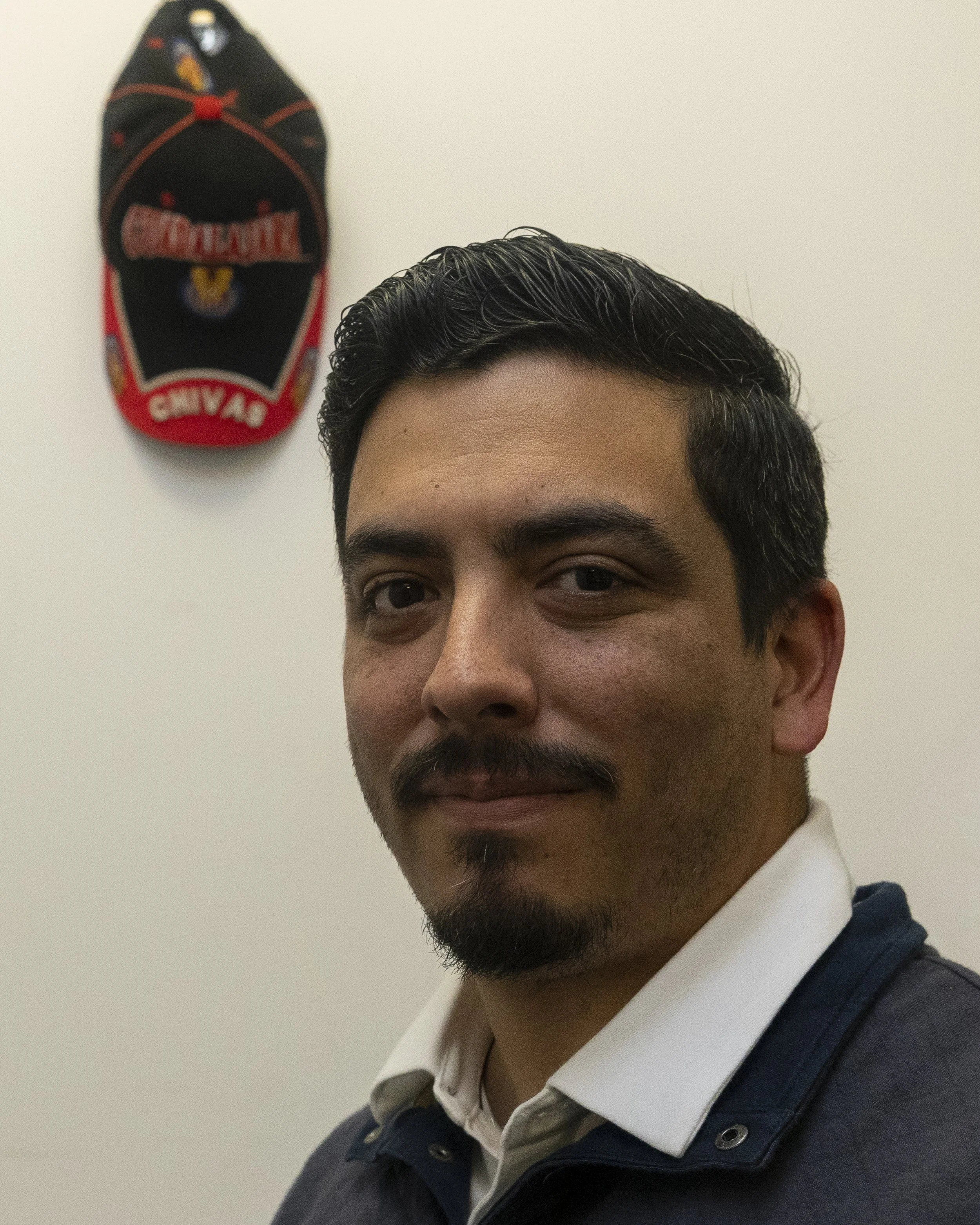  Santa Monica College program manager Luis Jauregui poses in front of a Chivas De Guadalajara soccer team hat that belonged to a former student on Thursday, June 4, 2026, inside his office in Santa Monica, Calif. The hat serves as a reminder of the s