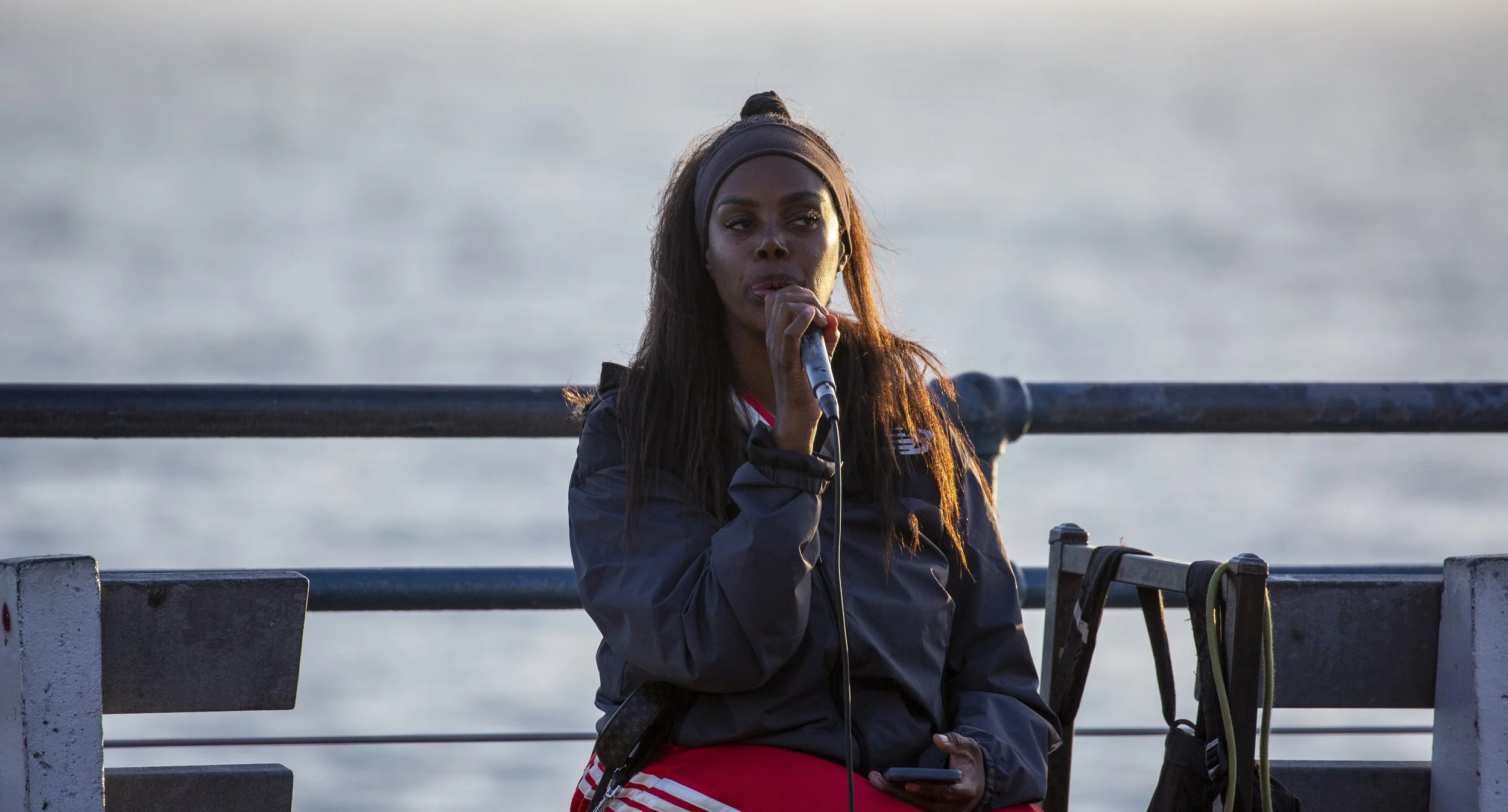  An unidentified singer sits by the railing and performs with a handheld microphone at the Santa Monica Pier in Santa Monica, Calif., on Friday, May 1, 2026. (Jinhao Tian | The Corsair) 