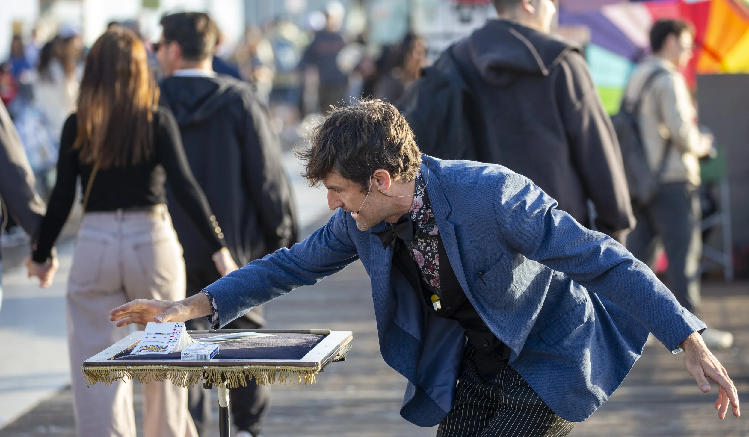  Street magician Jesse Mock reaches toward a deck of playing cards on his table while performing a card trick for visitors walking along the Santa Monica Pier in Santa Monica, Calif., on Friday, May 1, 2026. (Jinhao Tian | The Corsair) 