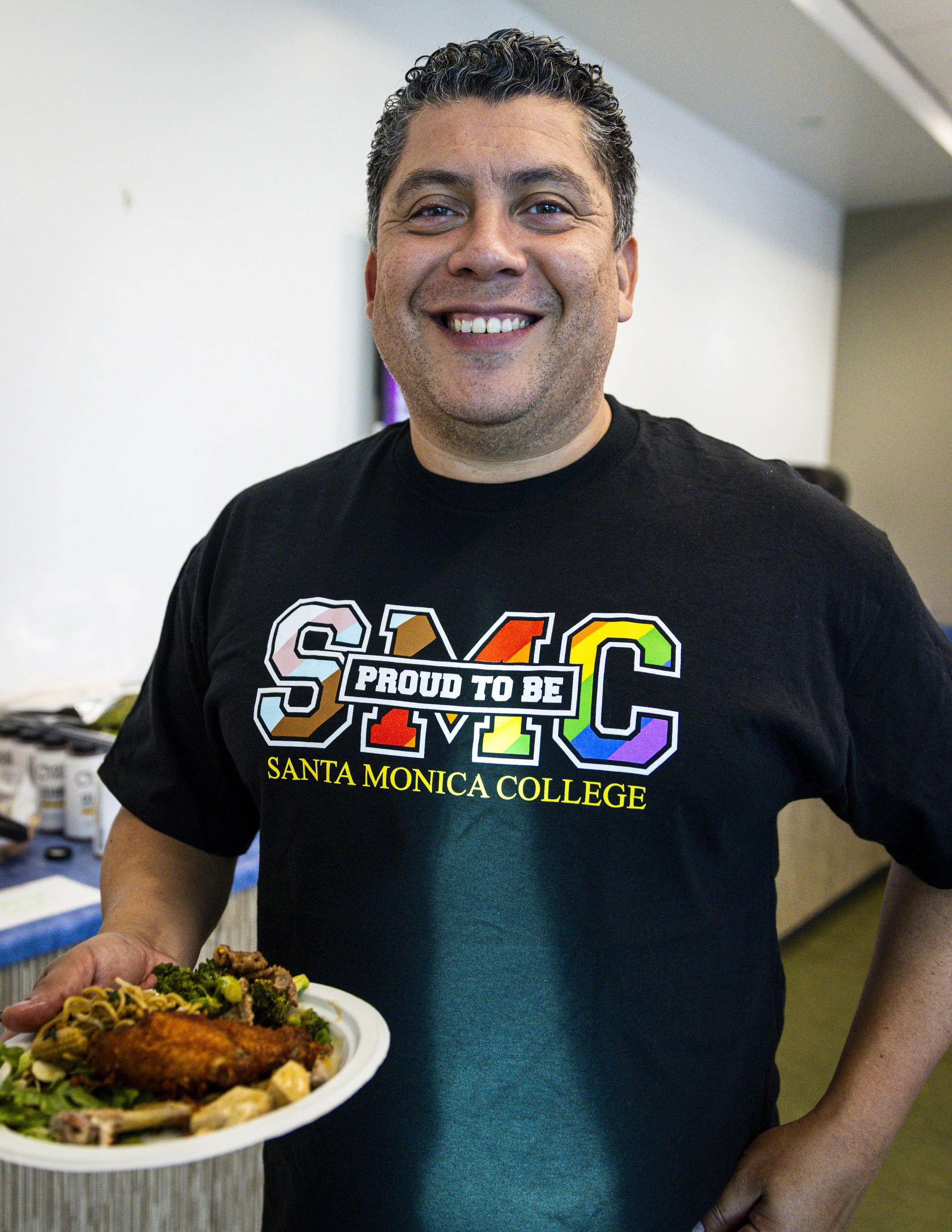  Santa Monica College (SMC) Student Services Specialist, Peer Navigators, Edwin Cruz grabs some food during the Student Equity Center celebration for LGBTQIA2S+ graduates from the Class of 2026 on Wednesday, May 27, 2026, in the Student Services Cent