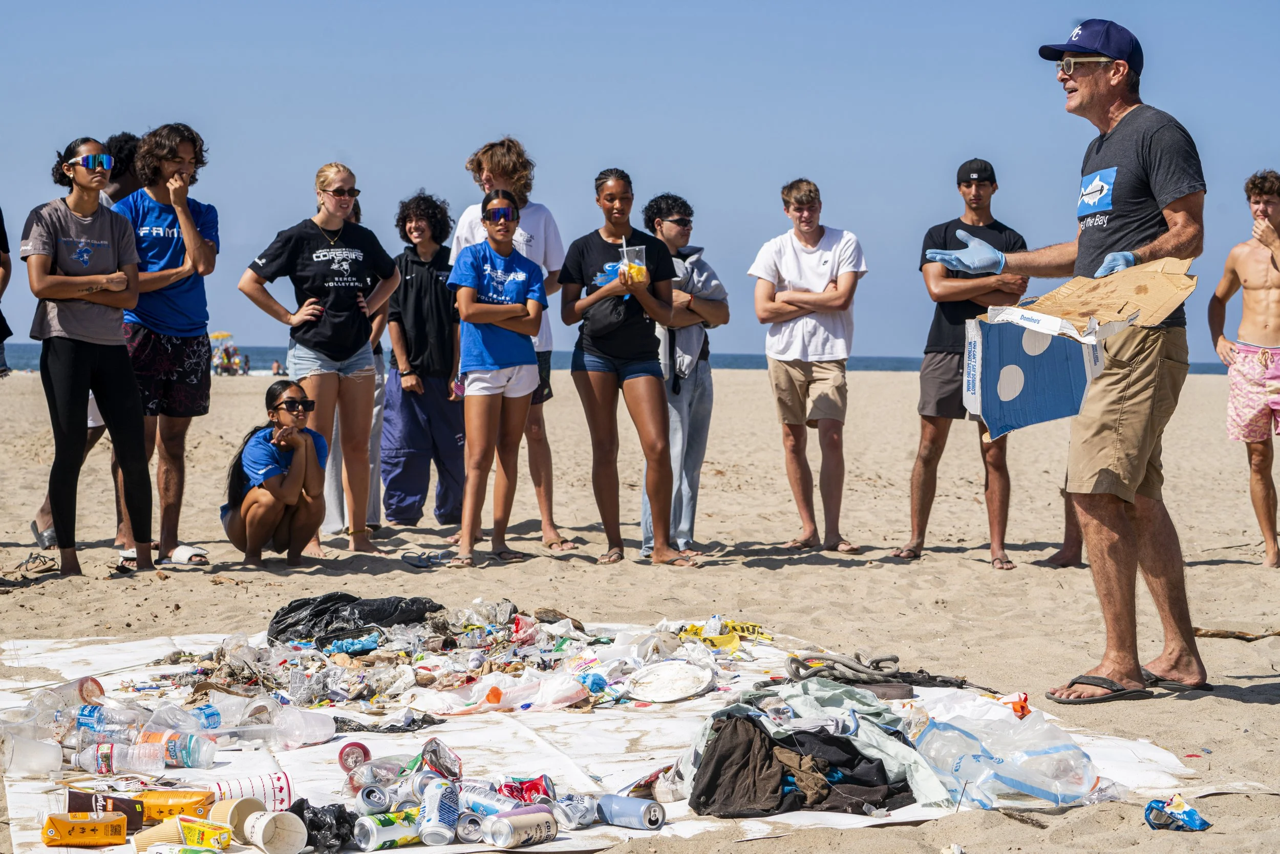  Site Captain of the coastal clean up & Santa Monica Sustainability Director Ferris Kawar demonstrates that there are 7 types of plastic and what you can and cannot recycle a Pizza box being one of the may that cant be recycled & should always go in 