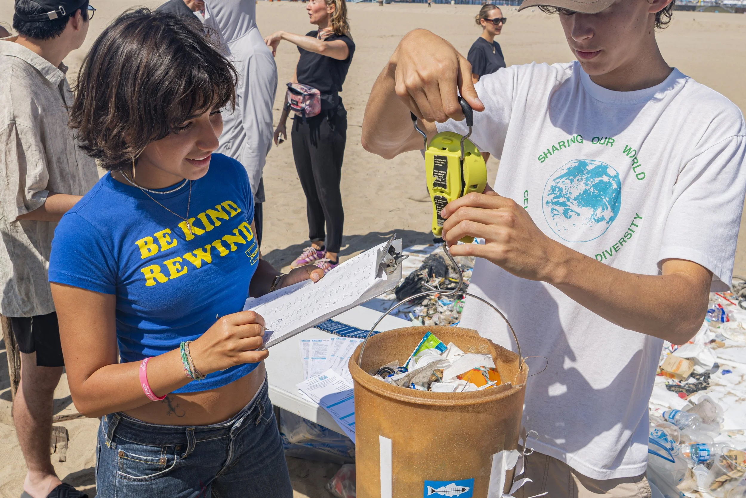  (L-R) Santa Monica College (SMC) student volunteer Alice Amorim & (SMC) Sustainability member Gabriel Batener weigh in incoming buckets filled with collected trash, Amorim recorded each individual bucket weight at the annual coastal cleanup in Santa