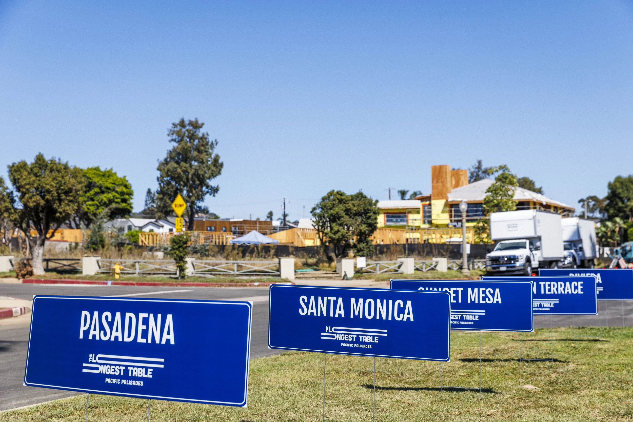  Signs display the names of neighborhoods affected by the 2025 Pacific Palisades fires during the second annual Longest Table Potluck Picnic Sunday, Oct. 4, 2026, on Pampas Ricas Blvd. in Pacific Palisades, Calif. Two years after the fires, the Pacif