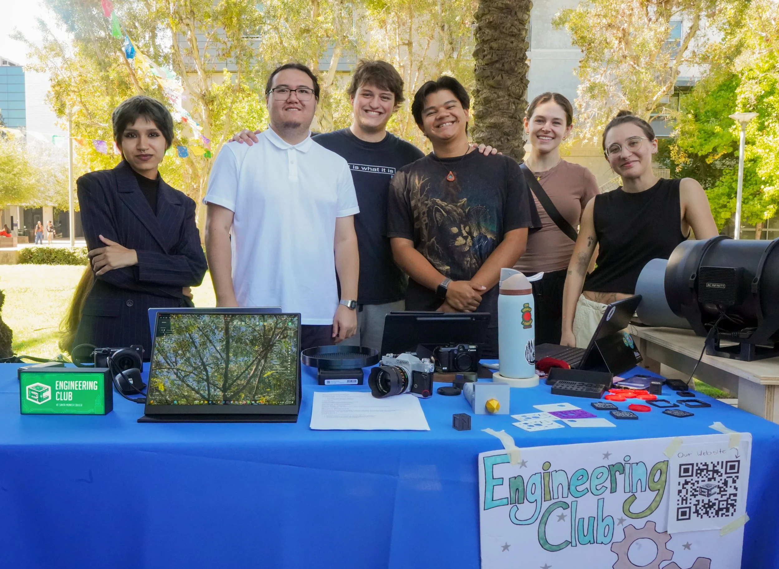  Engineering Club president and mechanical engineering major Thomas Yamaba (second from left, in white shirt) stands with fellow members at their display table during a club awareness event at Santa Monica College on Friday, June 5, 2026. The student