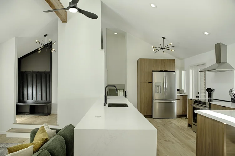 Kitchen with a white quartz island, wood cabinets, stainless appliances and a vaulted ceiling