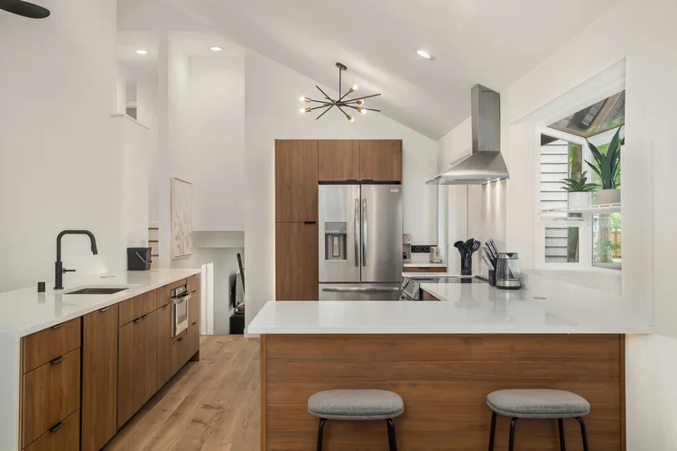 Modern kitchen with walnut cabinets, quartz peninsula, range hood and vaulted ceiling