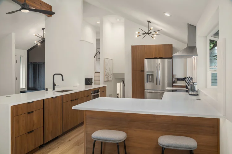 Kitchen peninsula with gray stools, walnut cabinets and sputnik light under vaulted ceiling