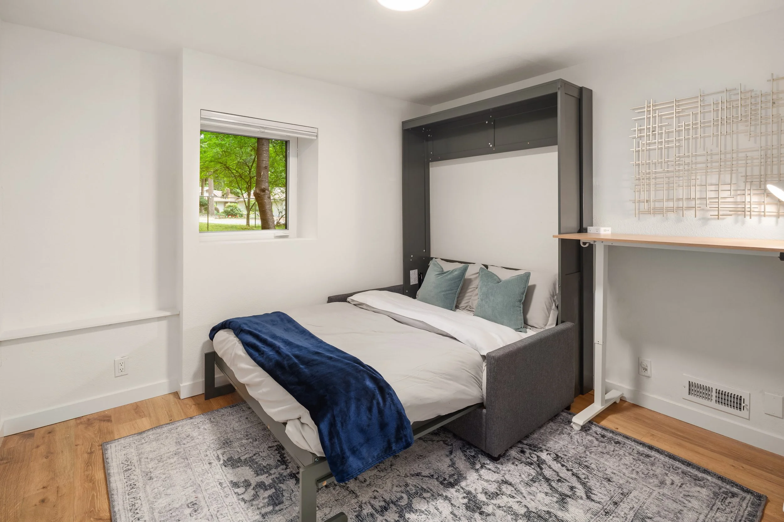 Fourth bedroom - with hidden murphy bed shown. Space is set up as office with hidden murphy bed, which easily folds down over sofa. Includes motorized sit/stand desk, 32” 4K monitor