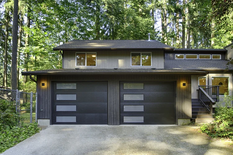 Front of Moss + Modern in Woodinville with black garage doors and wood siding