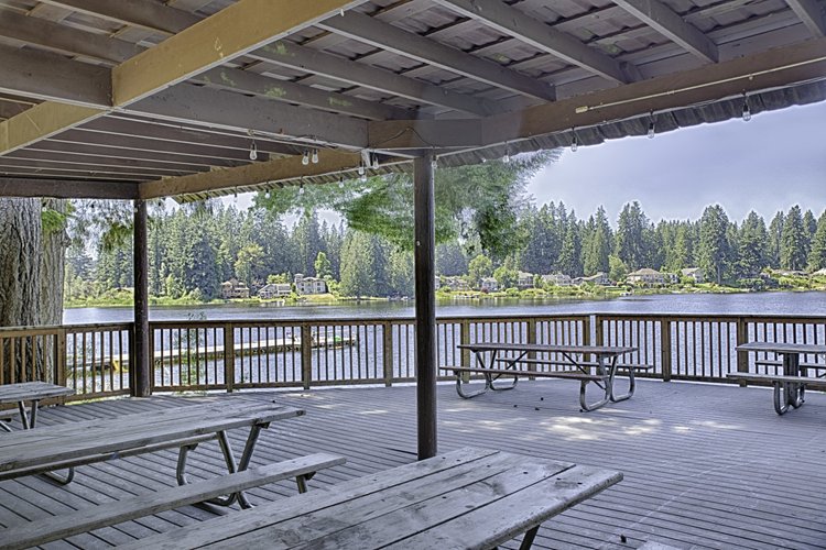 Covered lakeside pavilion with picnic tables overlooking Cottage Lake and homes