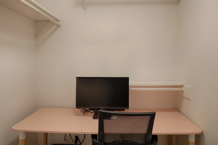 Small office nook with pink desk, monitor and mesh chair
