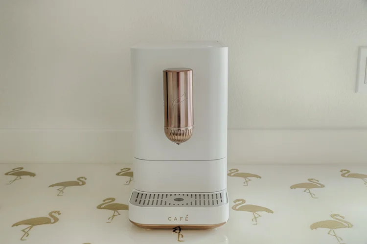 White Cafe espresso machine with copper spout on a gold flamingo-patterned counter